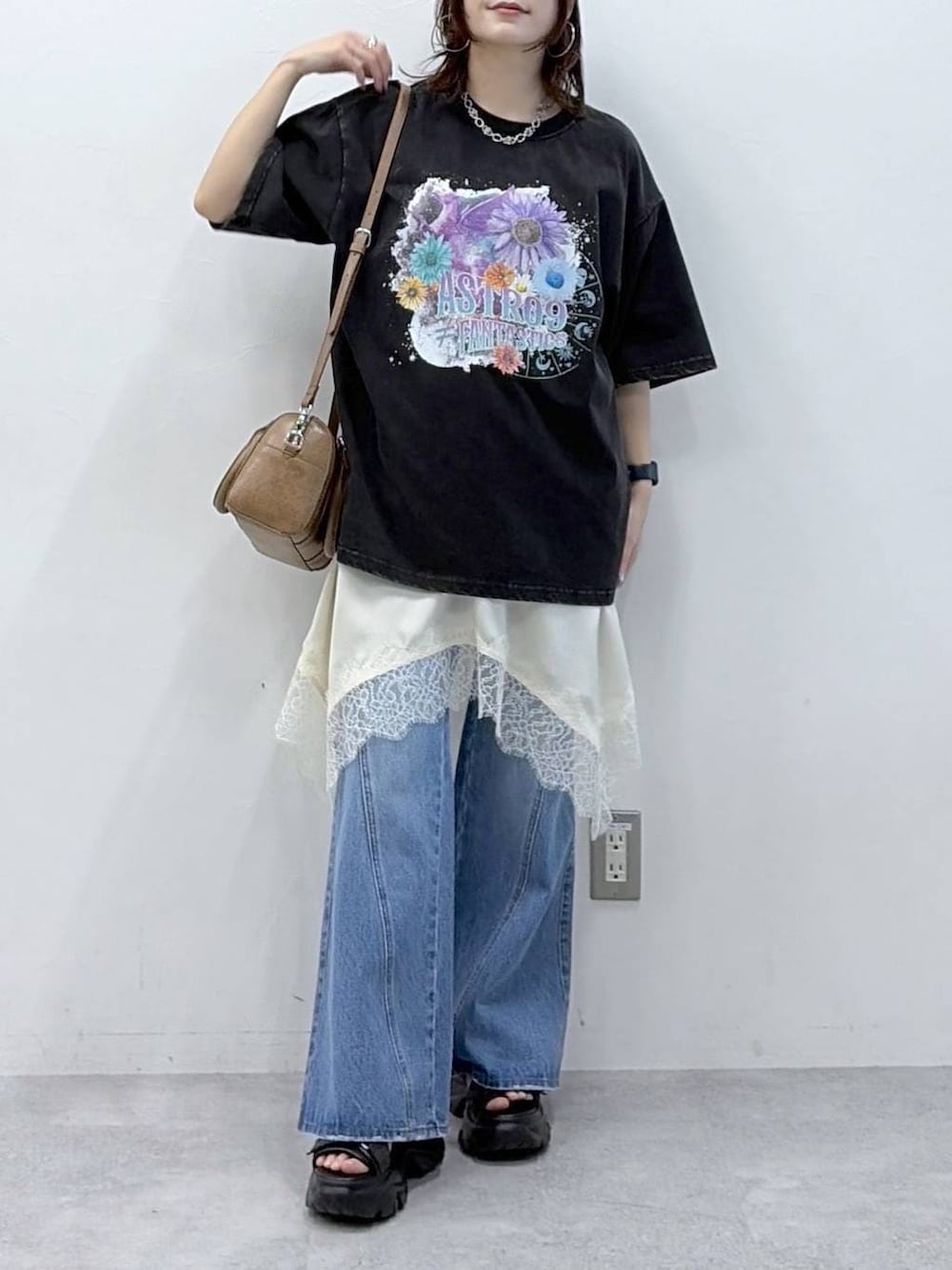 ブルー系のデニムパンツ、ブラウン系のボストンバッグ、ホワイト系のチュニックを着用したレディースの春コーディネートの3枚目の写真