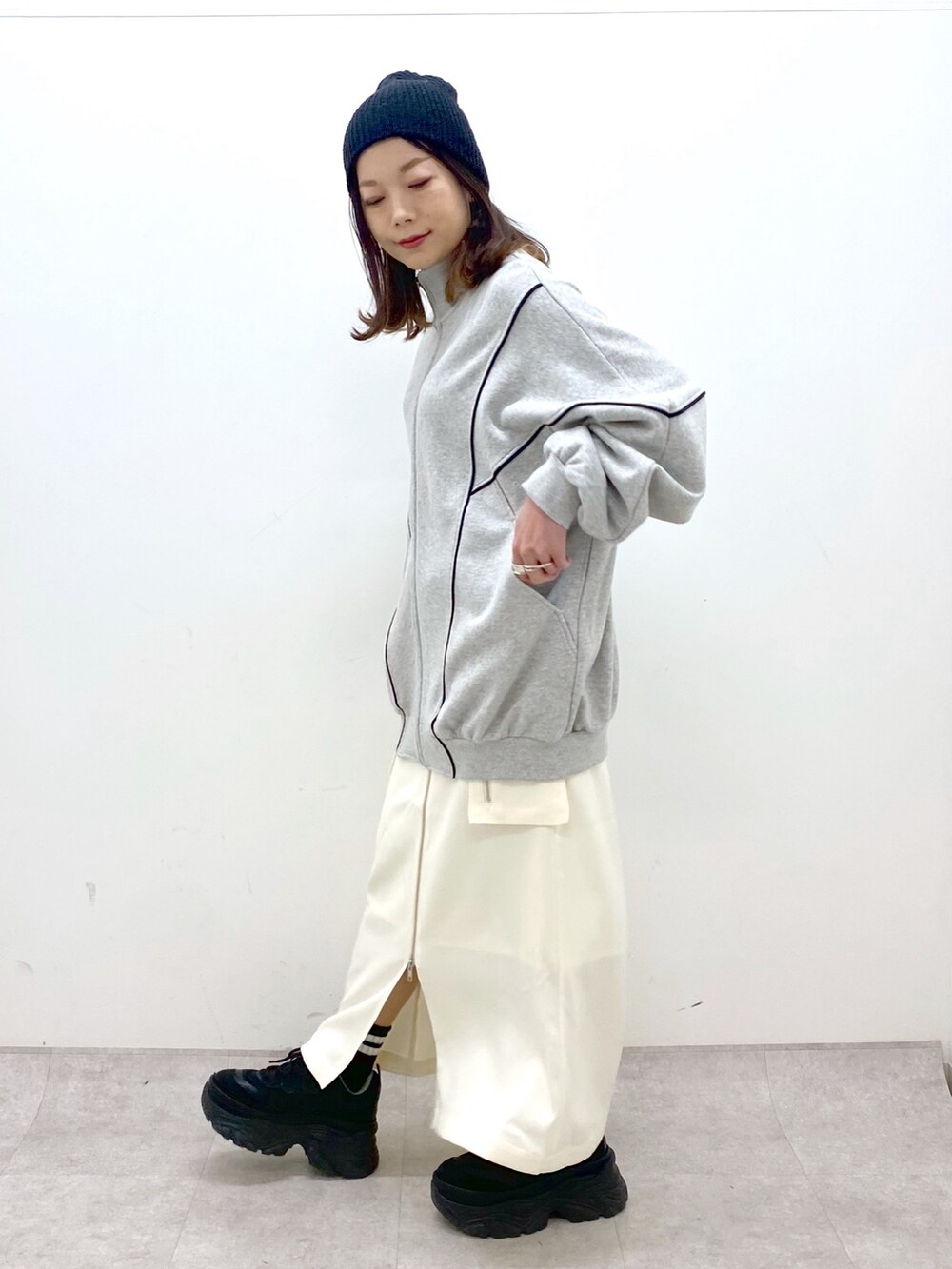 ホワイト系のスカート、ブラック系のスニーカー、グレー系のスウェットを着用したレディースの冬コーディネートの3枚目の写真