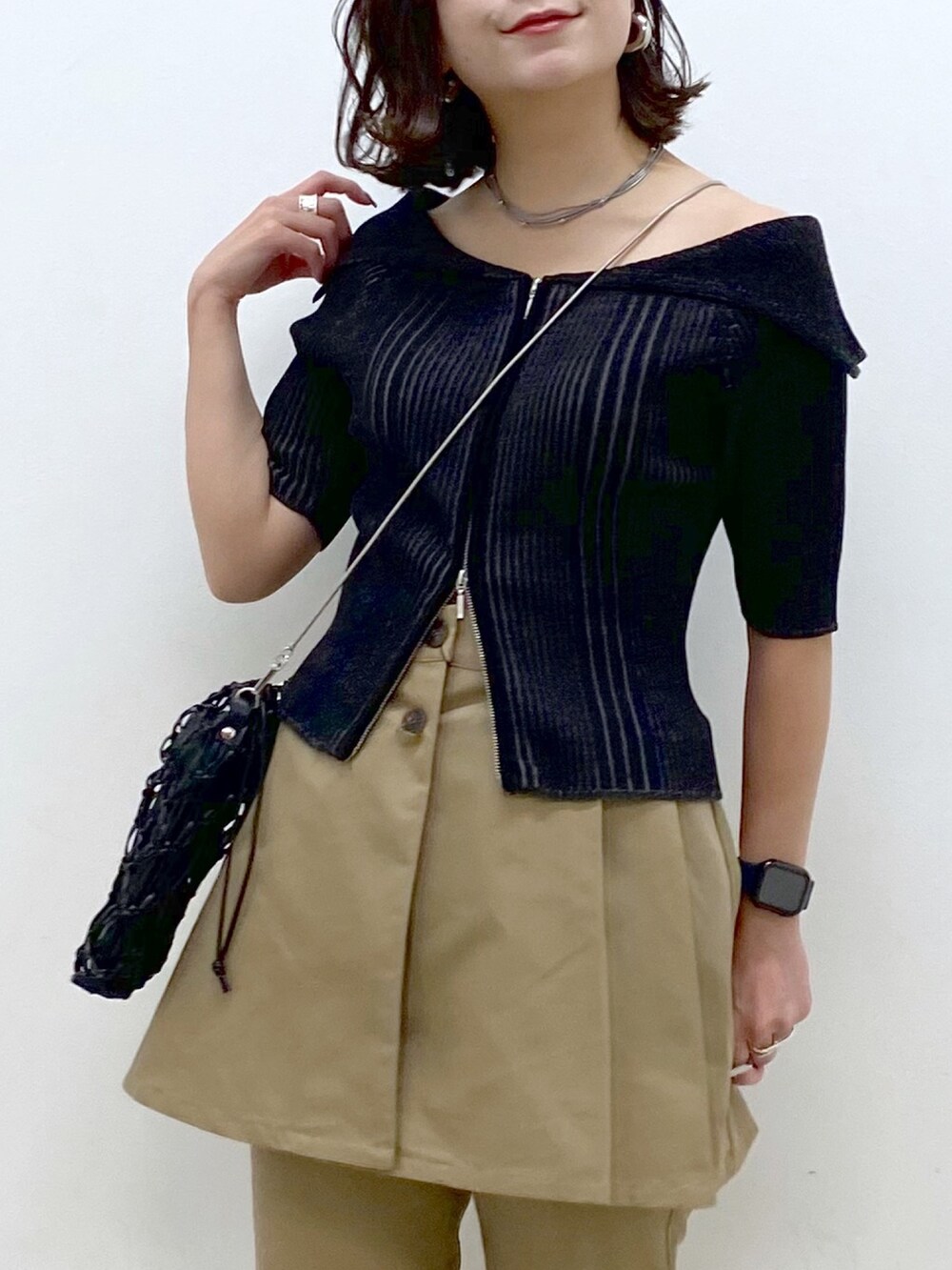 ブラック系のニット/セーター、ベージュ系のチノパンツ、ブラック系のショルダーバッグを着用したレディースの春コーディネートの2枚目の写真