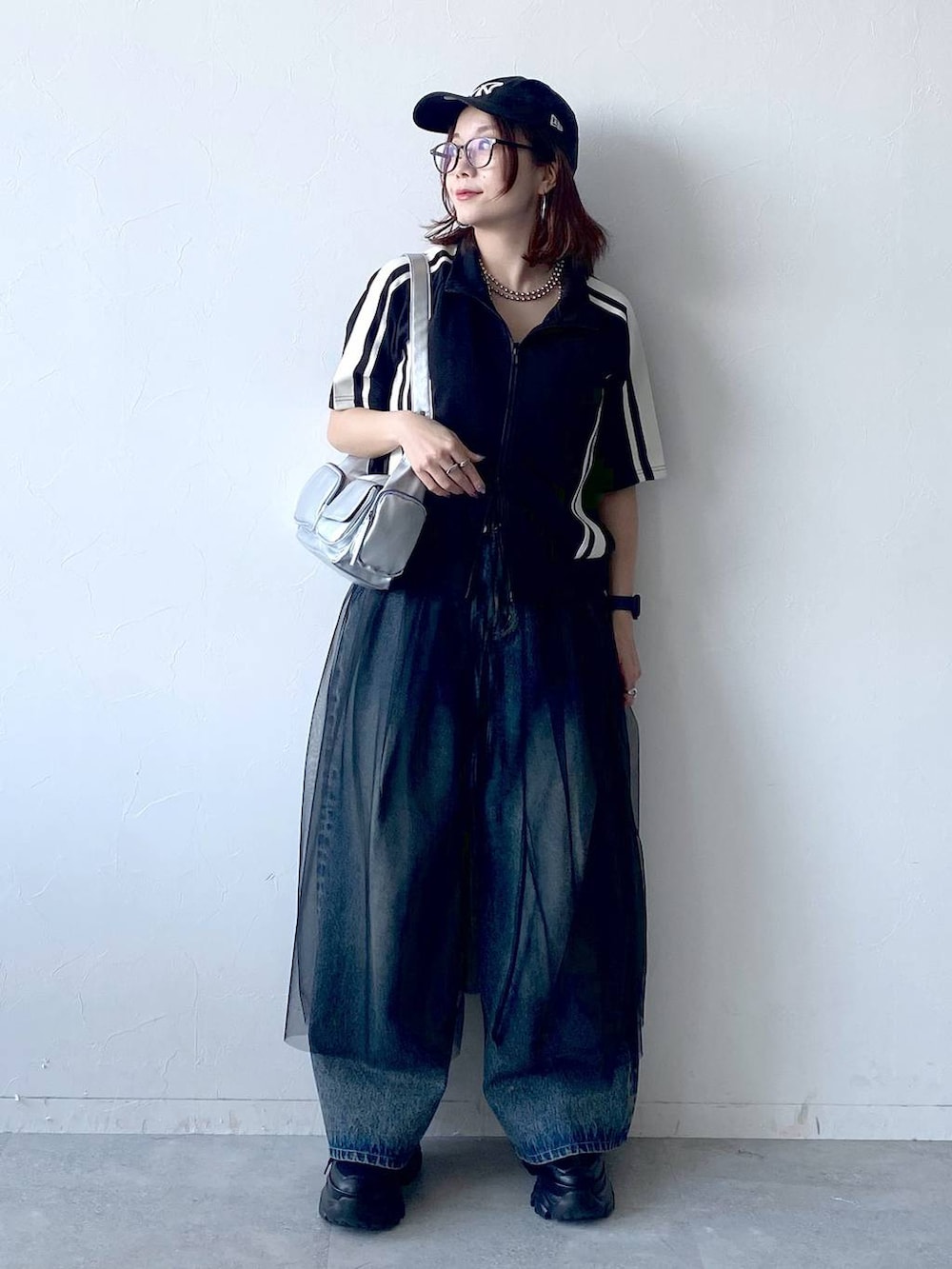 ブラック系のスニーカー、シルバー系のショルダーバッグ、ブルー系のデニムパンツを着用したレディースの夏コーディネートの9枚目の写真