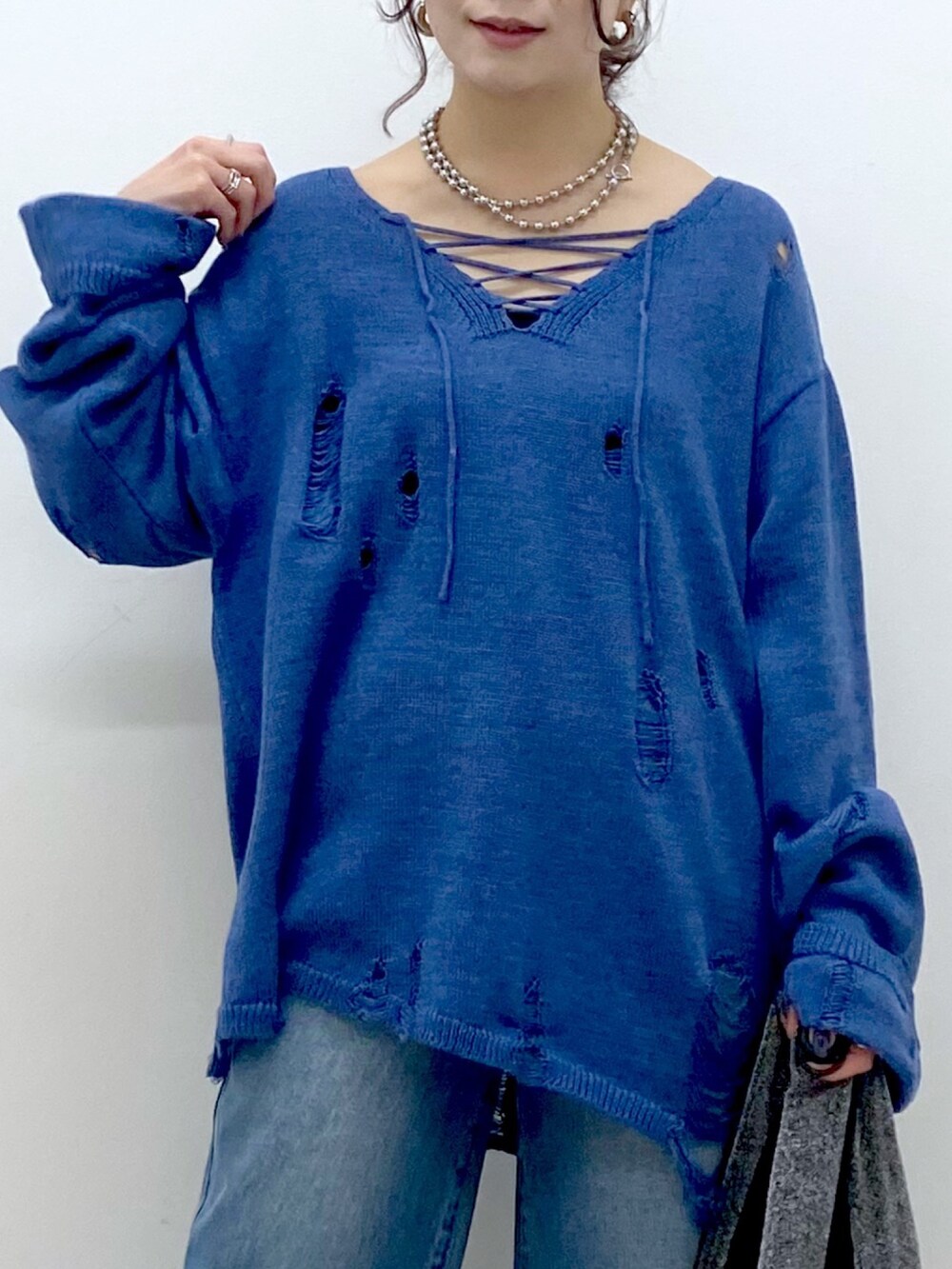 ブルー系のニット/セーター、ブルー系のデニムパンツ、ブラック系のトートバッグを着用したレディースの冬コーディネートの2枚目の写真