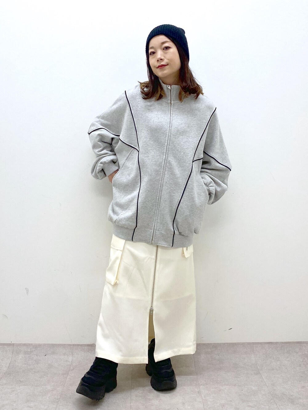 ホワイト系のスカート、ブラック系のスニーカー、グレー系のスウェットを着用したレディースの冬コーディネートの2枚目の写真