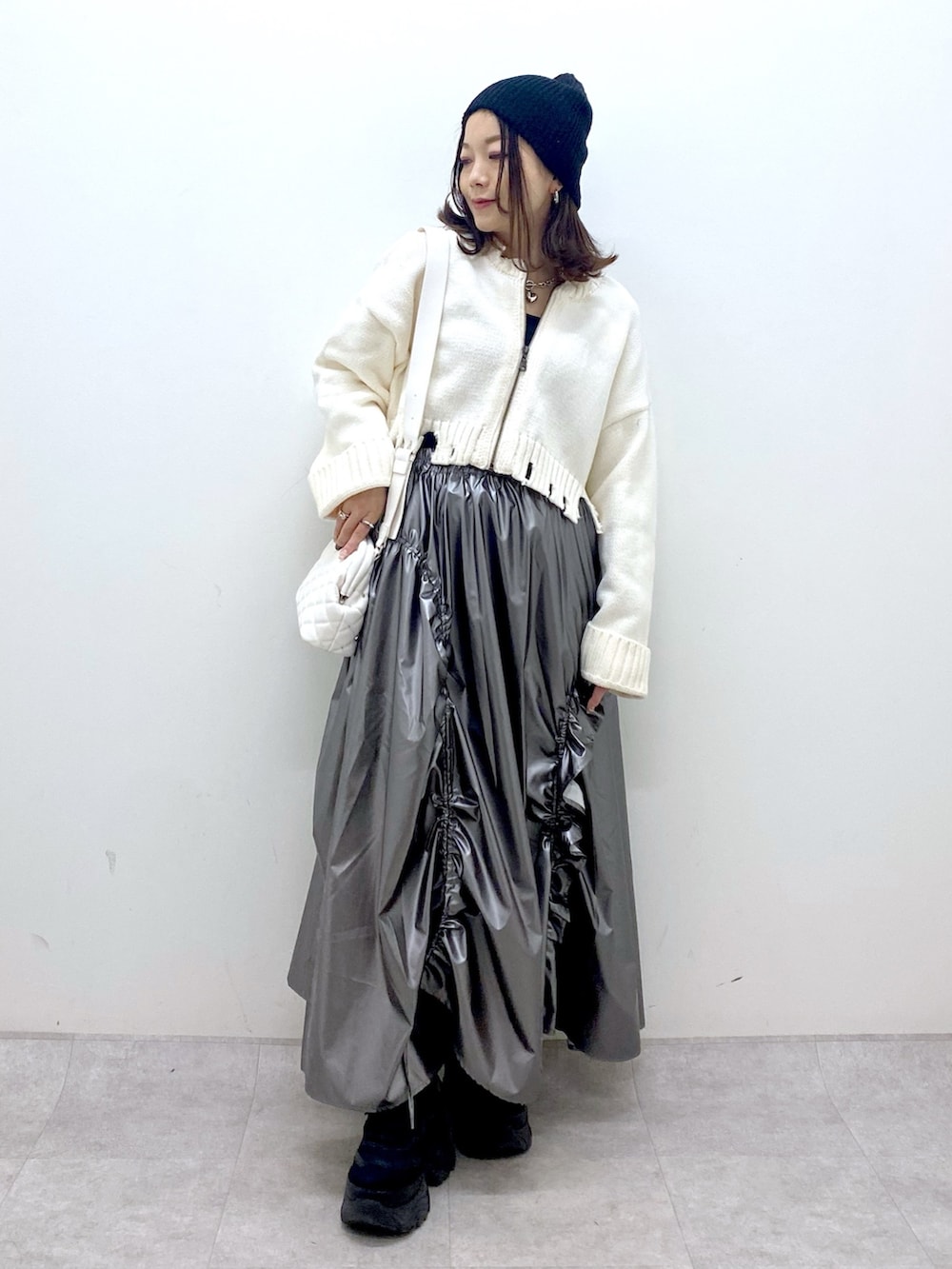 ホワイト系のニット/セーター、シルバー系のスカート、ホワイト系のショルダーバッグを着用したレディースの冬コーディネートの9枚目の写真