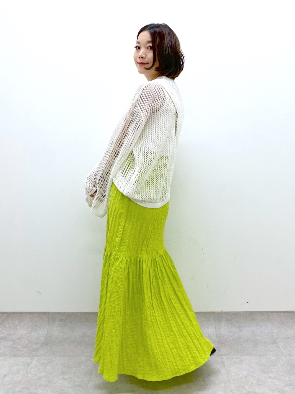 イエロー系のスカート、ホワイト系のバッグ、ホワイト系のトップスを着用したレディースの春コーディネートの2枚目の写真