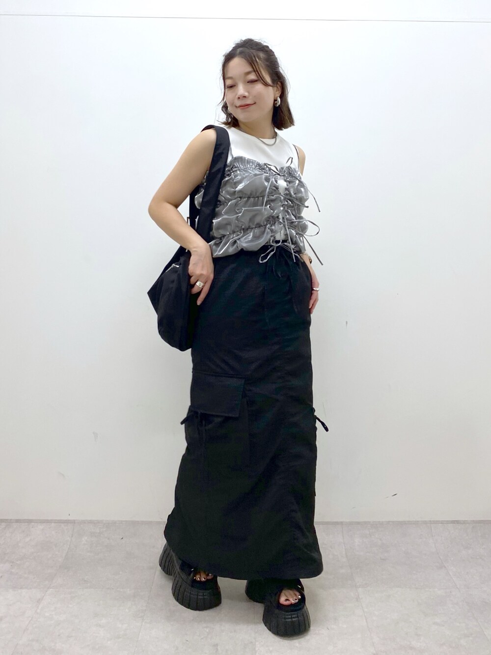 ブラック系のスニーカー、ブラック系のスカート、ブラック系のショルダーバッグを着用したレディースの夏コーディネートの4枚目の写真