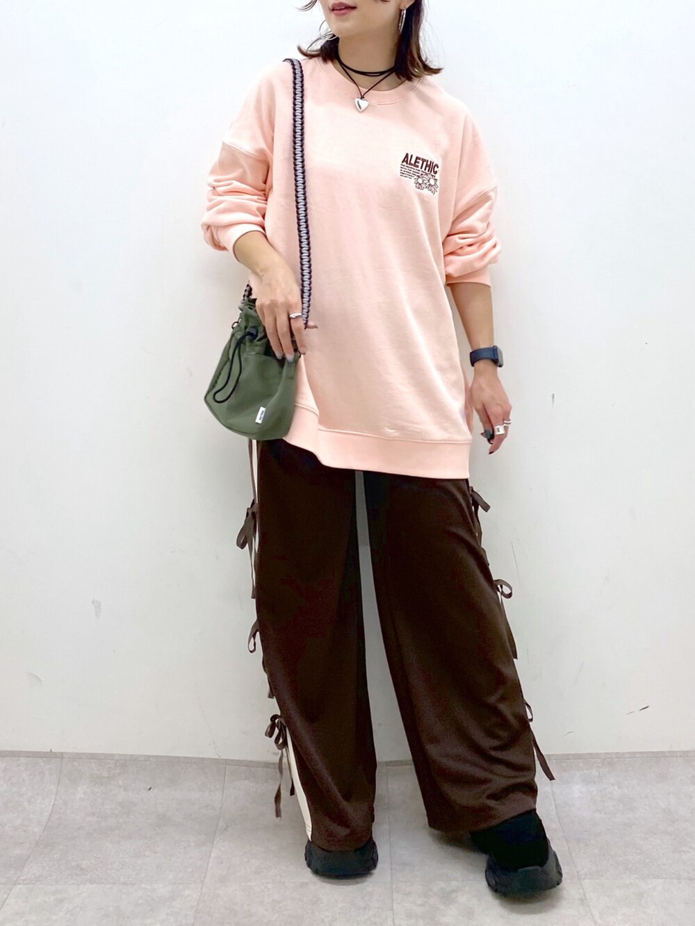 ピンク系のスウェット、グリーン系のショルダーバッグ、ブラウン系のその他パンツを着用したレディースの夏コーディネートの3枚目の写真