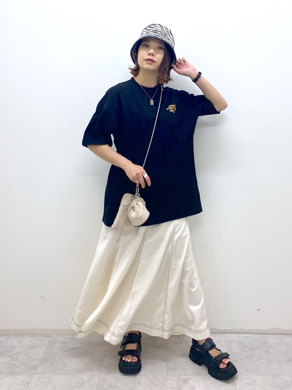 ベージュ系のショルダーバッグ、ブラック系のサンダル、ブラック系のTシャツ/カットソーを着用したレディースの夏コーディネートの5枚目の写真