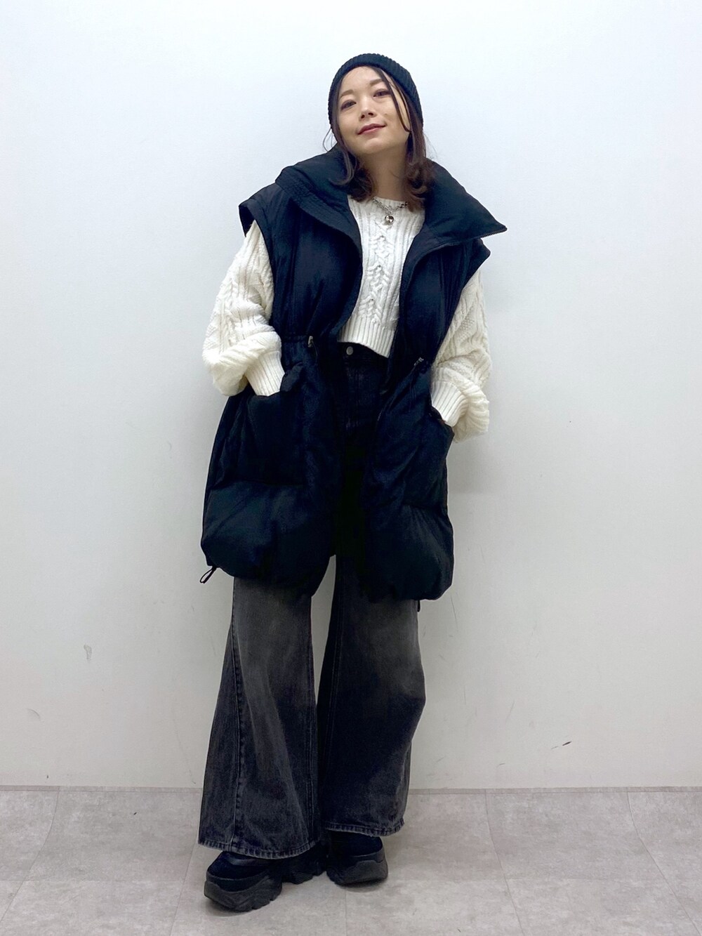 ブラック系のブルゾン、ホワイト系のニット/セーター、ブラック系のデニムパンツを着用したレディースの冬コーディネートの9枚目の写真