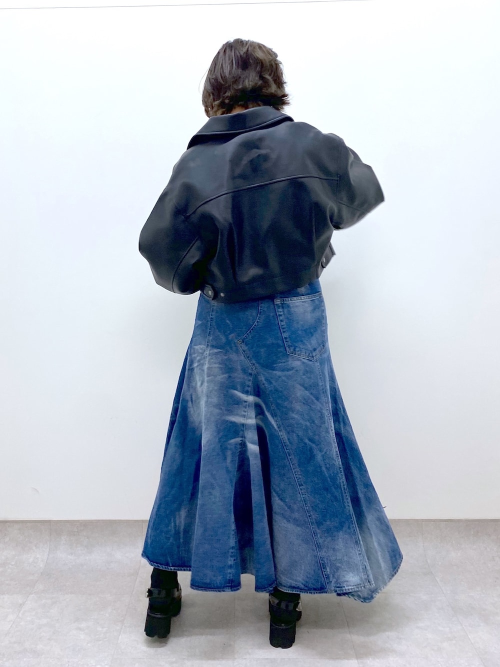 ブルー系のスカート、ブラック系のトップス、ブラック系のローファーを着用したレディースの春コーディネートの3枚目の写真