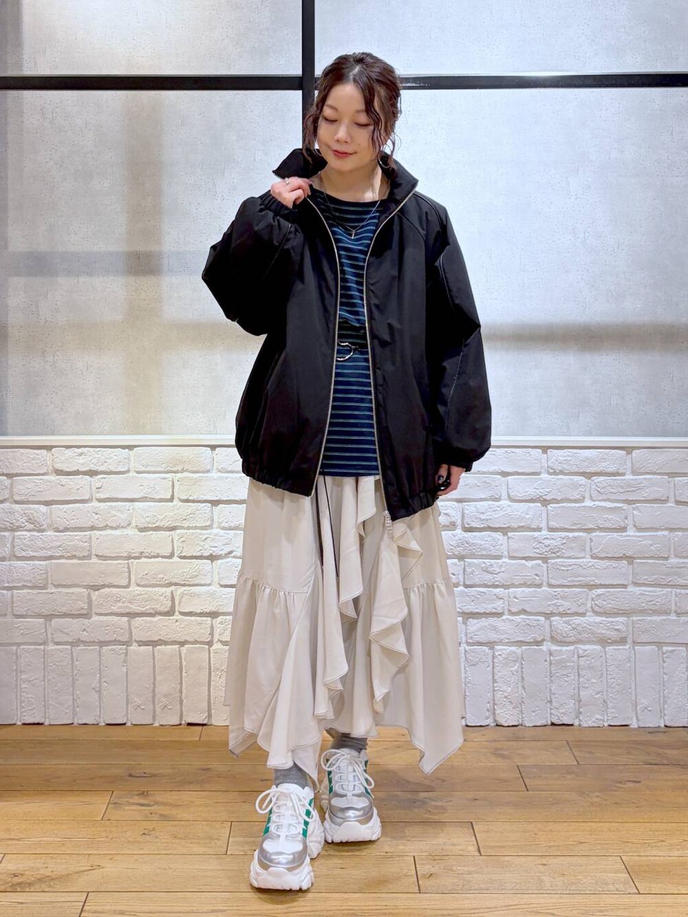 ホワイト系のスニーカー、ベージュ系のスカート、ブラック系のナイロンジャケットを着用したレディースの冬コーディネートの9枚目の写真