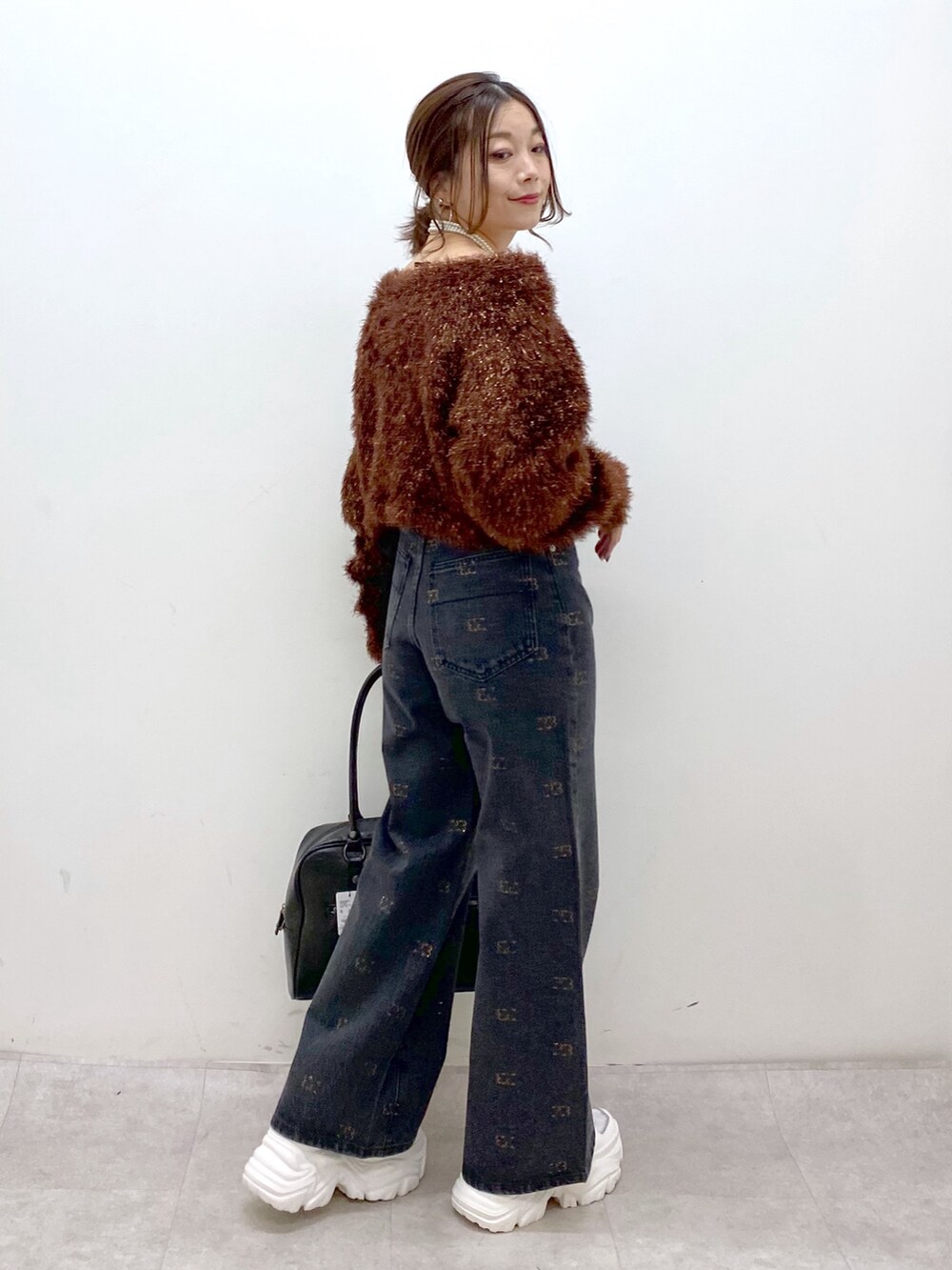 ブラウン系のニット/セーター、ブラック系のボストンバッグ、ホワイト系のスニーカーを着用したレディースの冬コーディネートの8枚目の写真