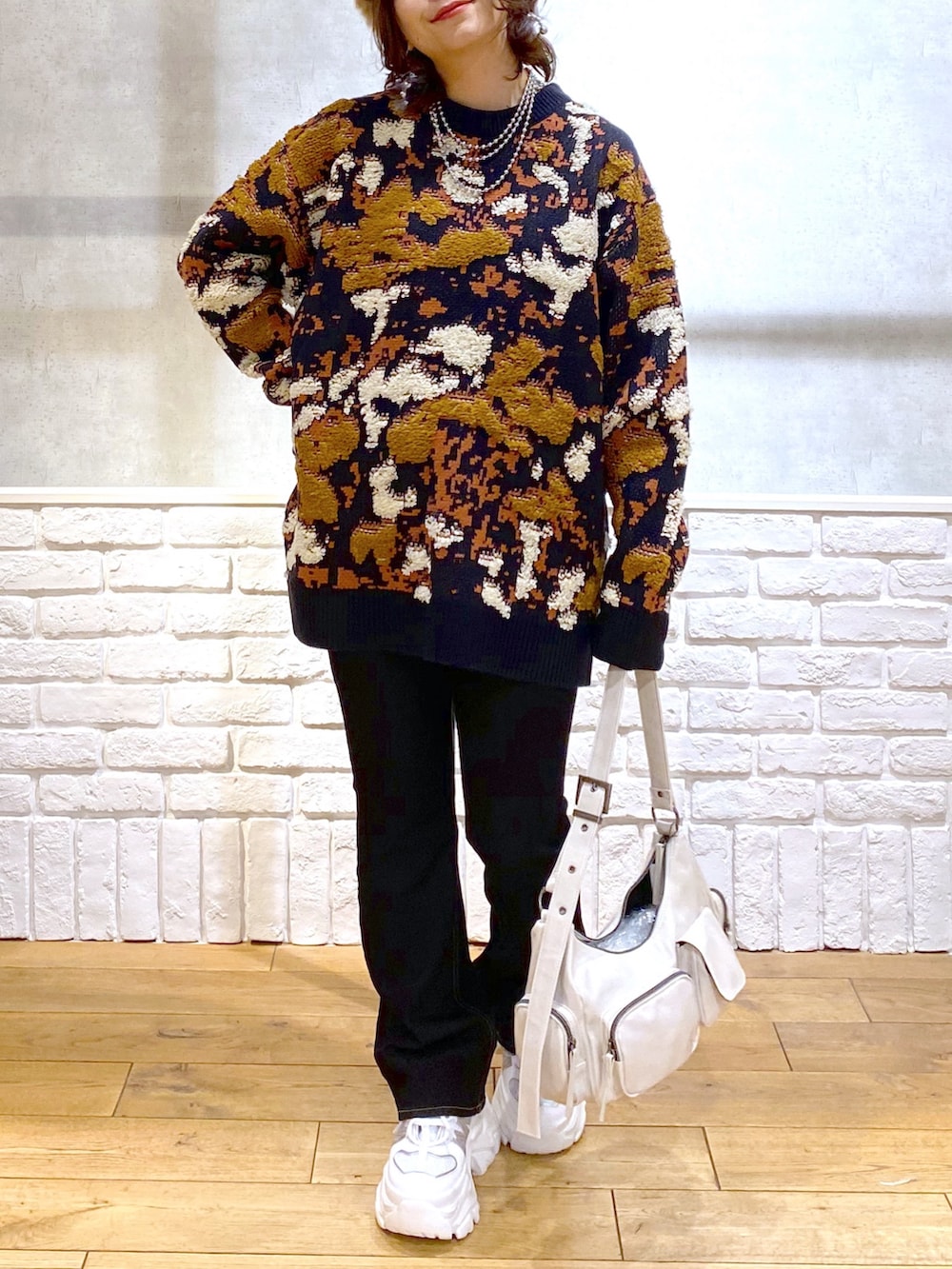 ブルー系のニット/セーター、ブルー系のデニムパンツ、ホワイト系のショルダーバッグを着用したレディースの冬コーディネートの3枚目の写真