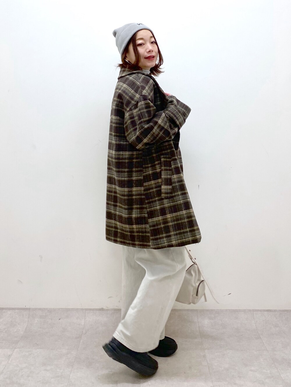 ブラウン系のテーラードジャケット、グレー系のデニムパンツ、ホワイト系のショルダーバッグを着用したレディースの冬コーディネートの5枚目の写真