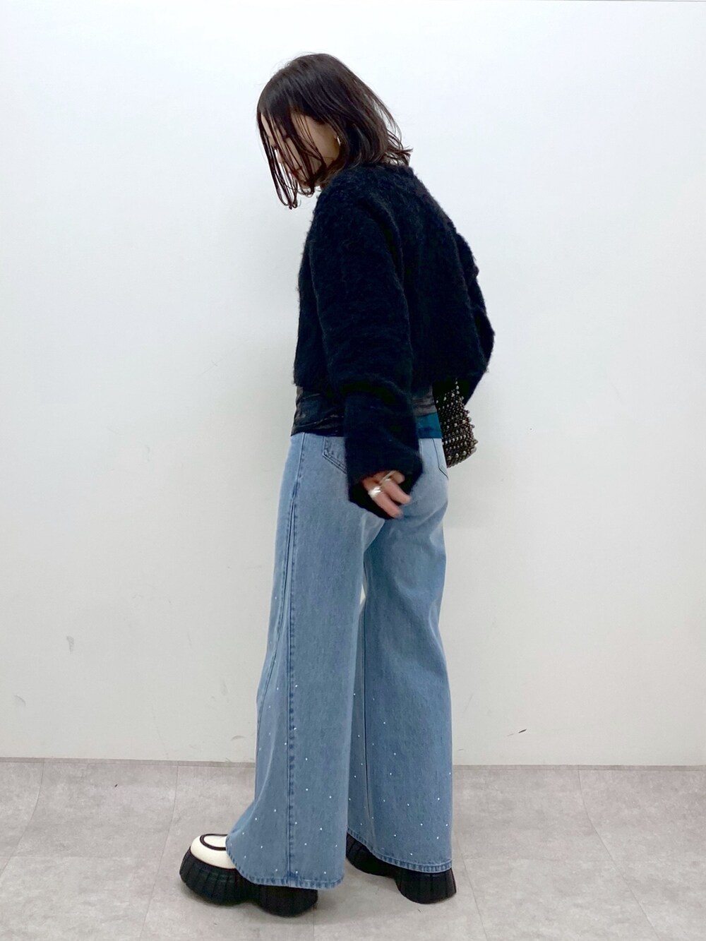 ブラック系のニット/セーター、ブルー系のデニムパンツ、ホワイト系のローファーを着用したレディースの冬コーディネートの6枚目の写真