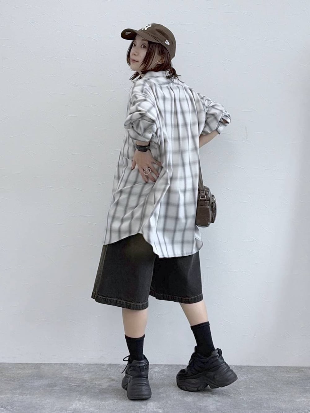 ブラック系のスニーカー、ブラウン系のショルダーバッグ、ホワイト系のシャツ/ブラウスを着用したレディースの春コーディネートの3枚目の写真