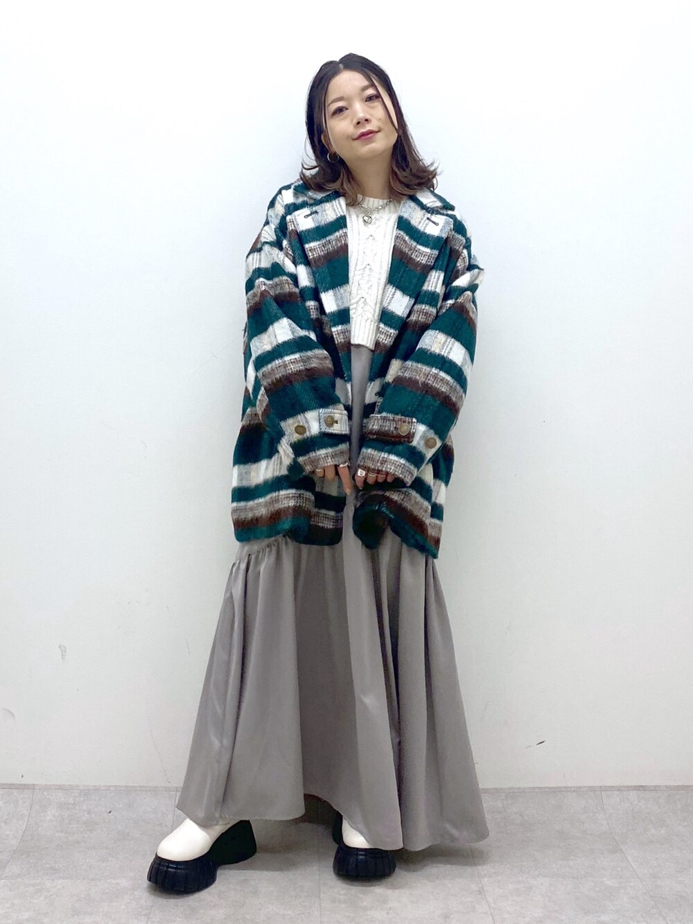 グリーン系のその他アウター、ホワイト系のニット/セーター、ホワイト系のワンピースを着用したレディースの冬コーディネートの9枚目の写真