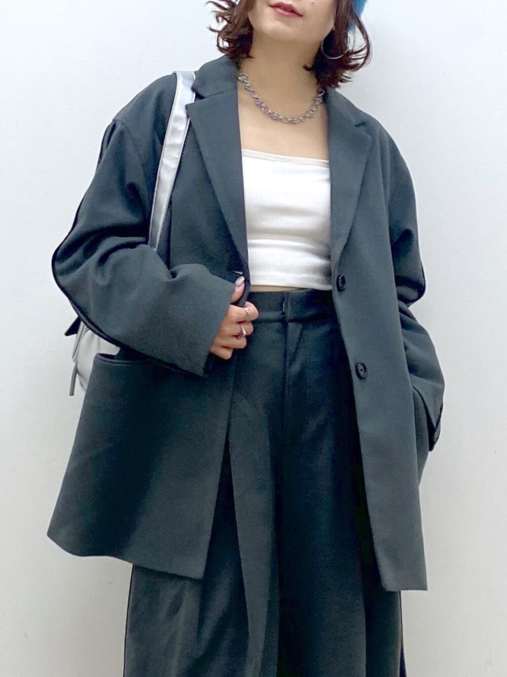 グレー系のスラックス、シルバー系のパンプス、シルバー系のショルダーバッグを着用したレディースの秋コーディネートの2枚目の写真