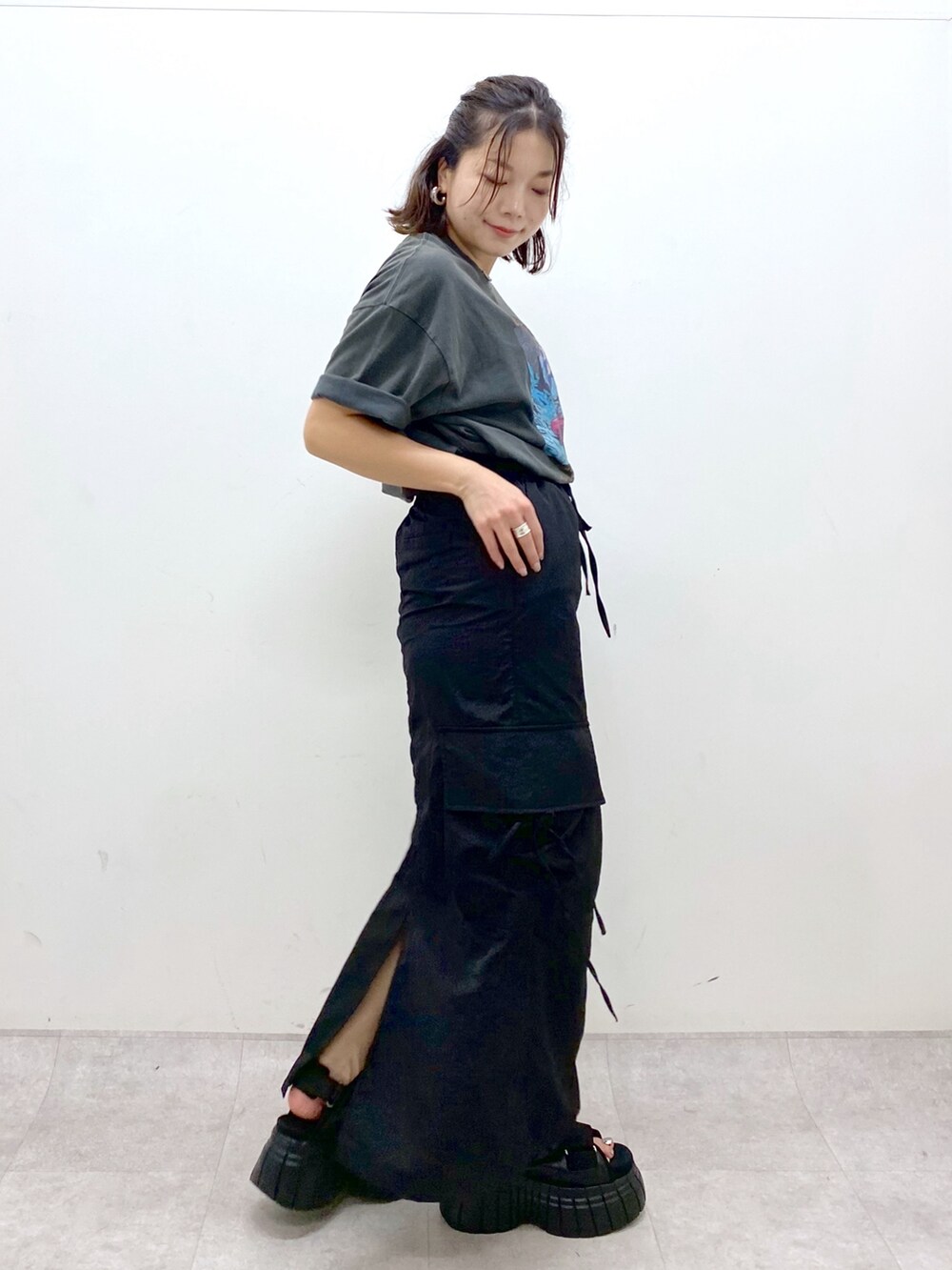 グレー系のTシャツ/カットソー、ブラック系のスカート、ブラック系のスニーカーを着用したレディースの夏コーディネートの5枚目の写真