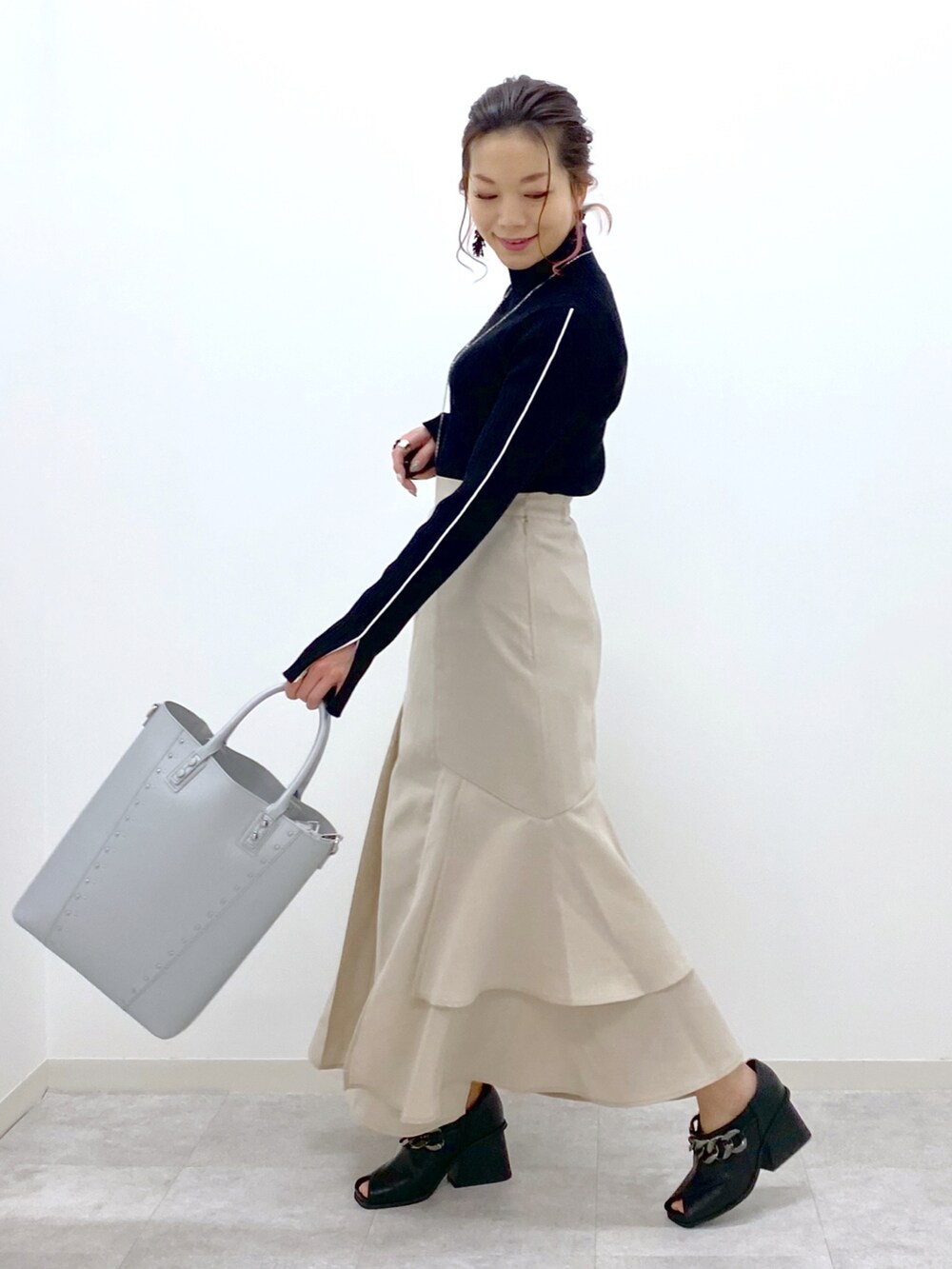 ブラック系のニット/セーター、ベージュ系のスカート、シルバー系のショルダーバッグを着用したレディースの冬コーディネートの2枚目の写真