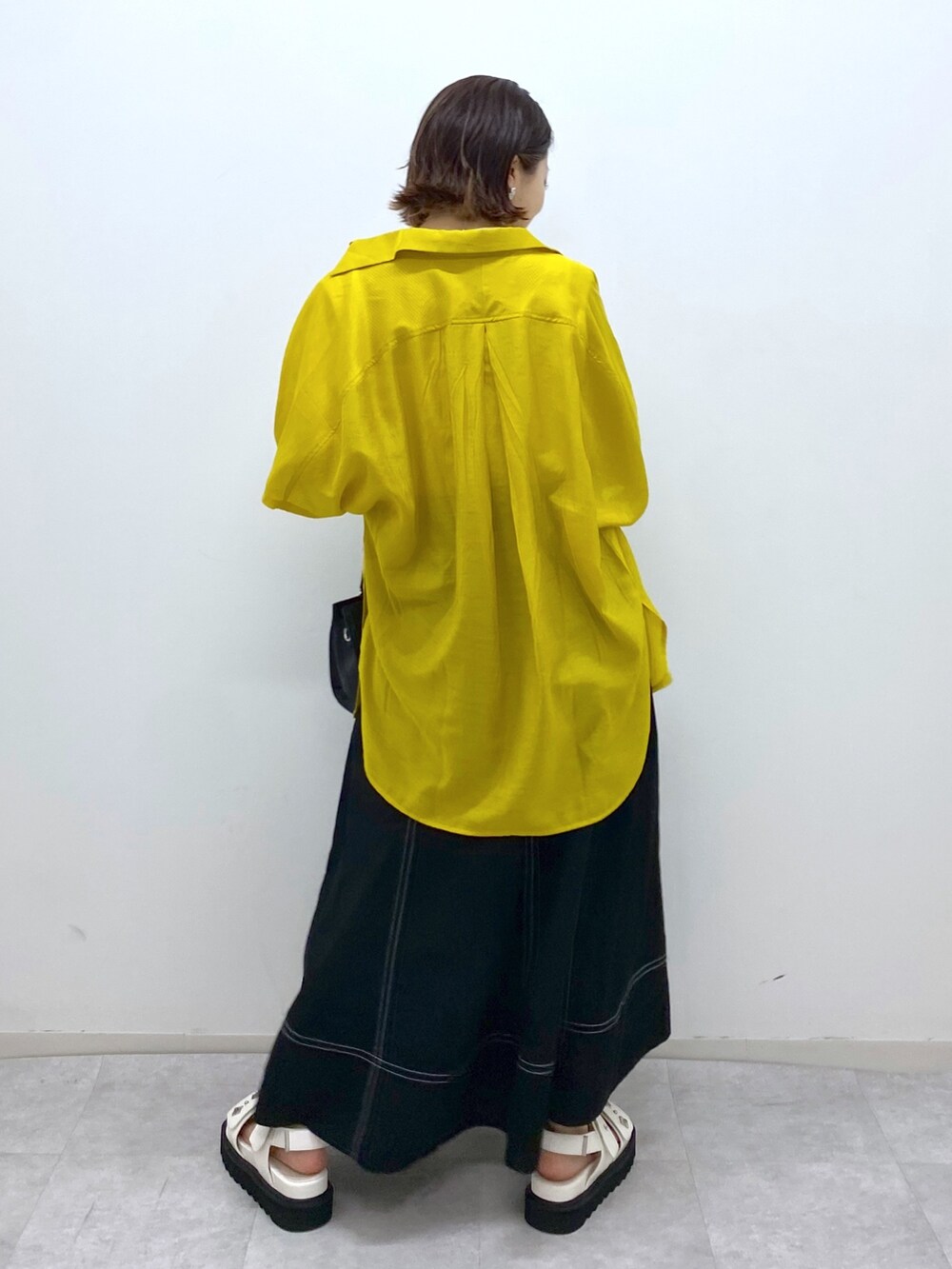 ホワイト系のトップス、イエロー系のシャツ/ブラウス、ブラック系のスカートを着用したレディースの夏コーディネートの3枚目の写真