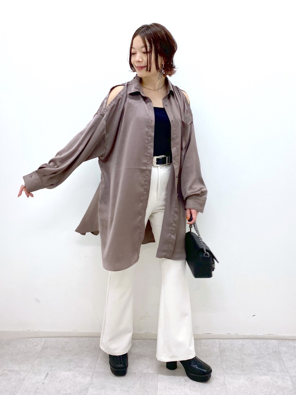 ホワイト系のパンツ、ブラック系のブーツ、ブラック系のバッグを着用したレディースの秋コーディネートの5枚目の写真