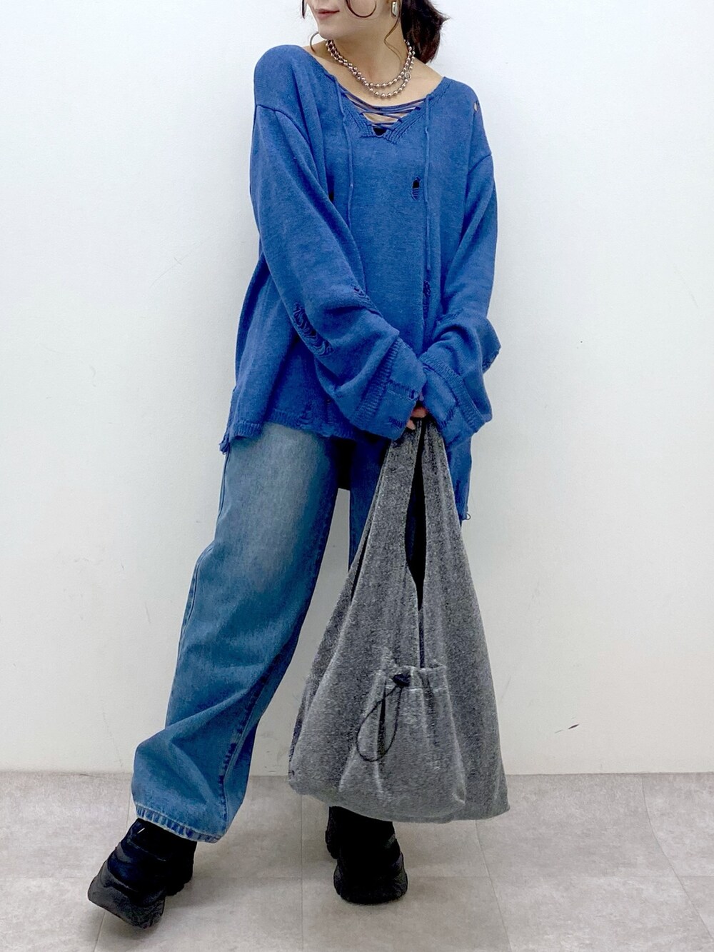 ブルー系のニット/セーター、ブルー系のデニムパンツ、ブラック系のトートバッグを着用したレディースの冬コーディネートの3枚目の写真