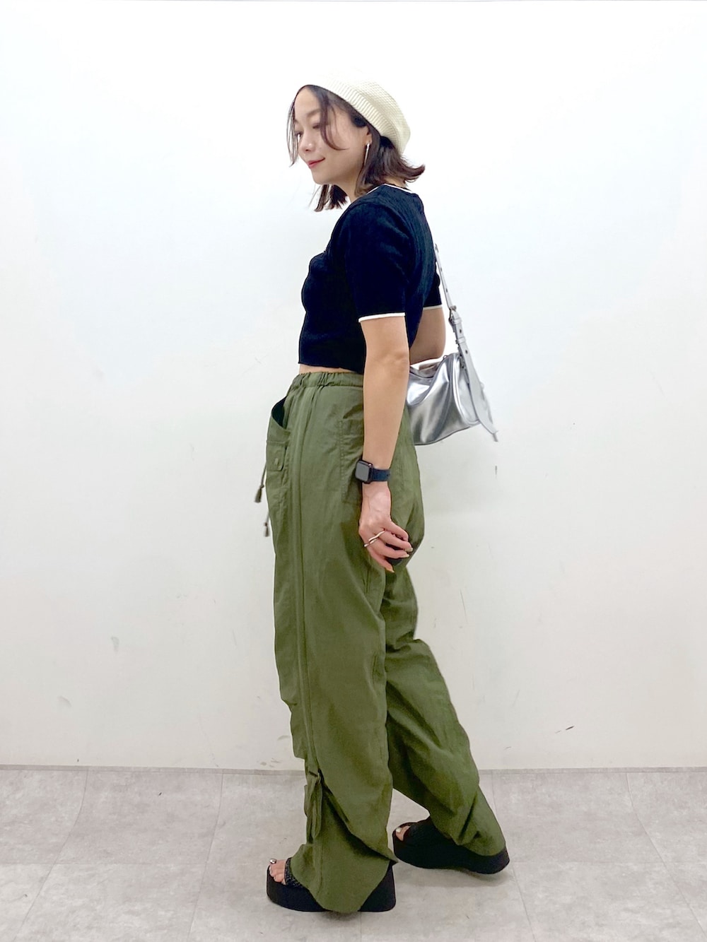 グリーン系のカーゴパンツ、ブラック系のサンダル、シルバー系のショルダーバッグを着用したレディースの夏コーディネートの5枚目の写真