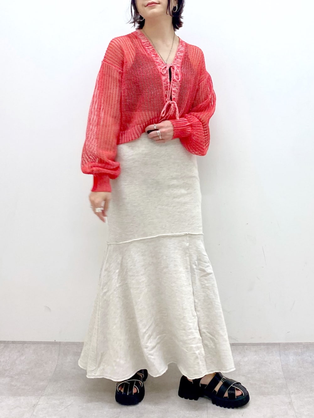 ベージュ系のスカート、レッド系のカーディガン/ボレロ、ブラック系のサンダルを着用したレディースの春コーディネートの4枚目の写真