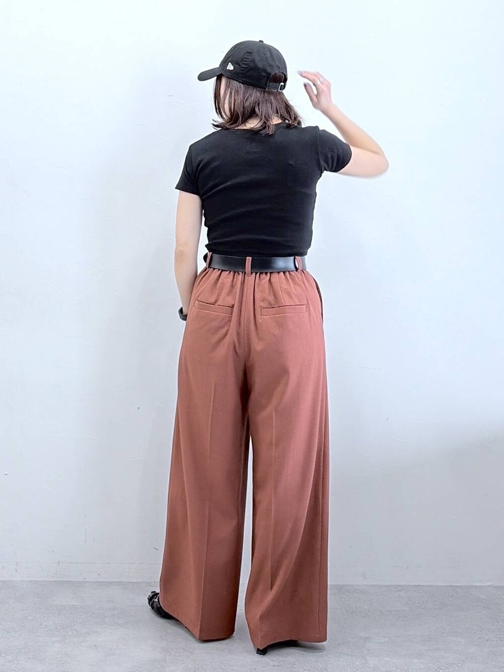 ブラウン系のスラックス、ブラック系のTシャツ/カットソー、ブラック系のキャップを着用したレディースの春コーディネートの6枚目の写真