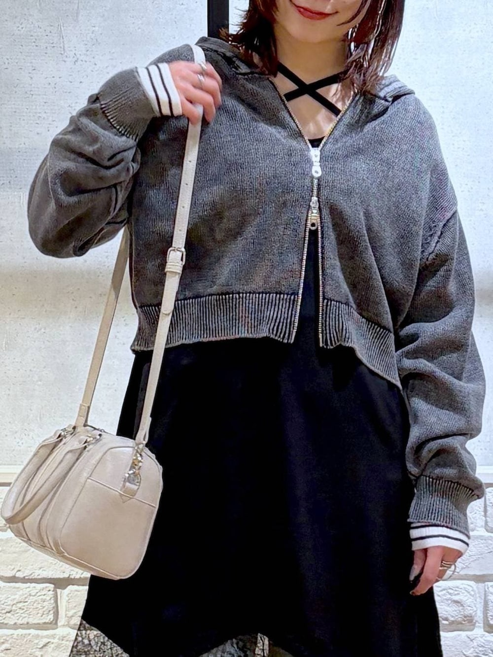 ブルー系のデニムパンツ、ホワイト系のボストンバッグ、ホワイト系のニット/セーターを着用したレディースの春コーディネートの2枚目の写真