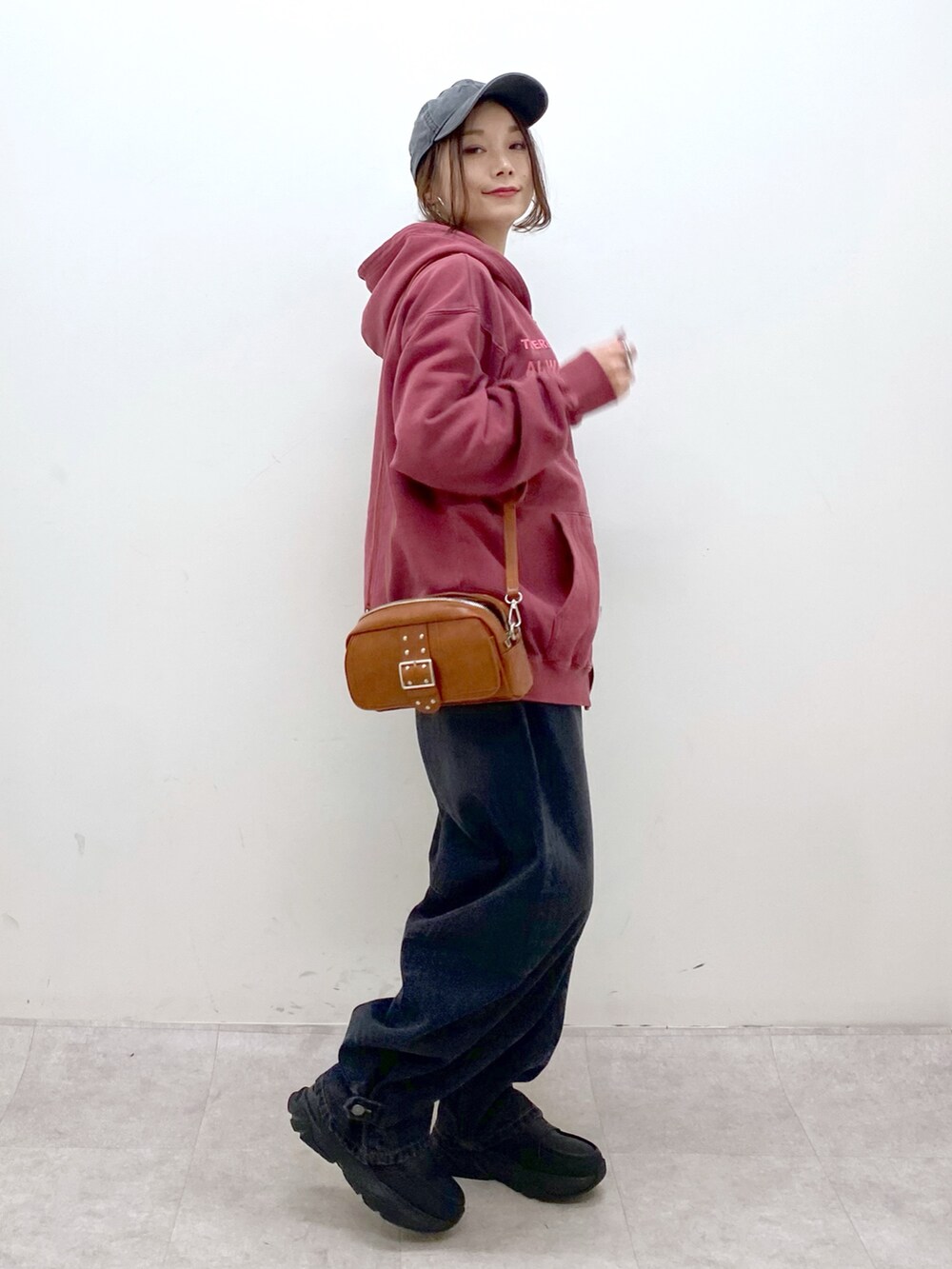 レッド系のスウェット、ブラック系のデニムパンツ、ブラック系のローファーを着用したレディースの冬コーディネートの7枚目の写真