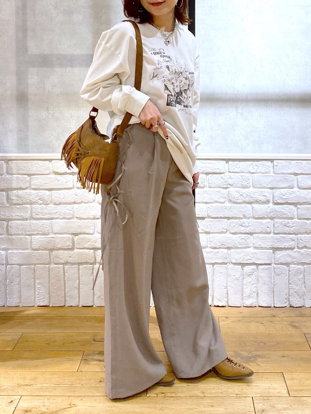 ブラウン系のスラックス、ベージュ系のショルダーバッグ、ブラウン系のパンプスを着用したレディースの春コーディネートの2枚目の写真