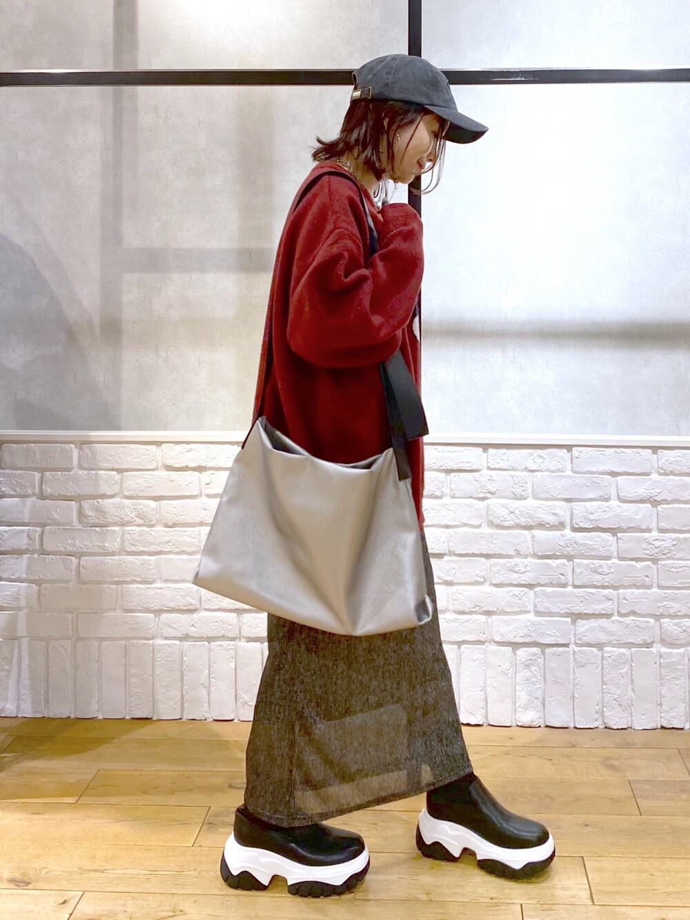 ブラック系のスカート、ブラック系のブーツ、シルバー系のトートバッグを着用したレディースの冬コーディネートの7枚目の写真