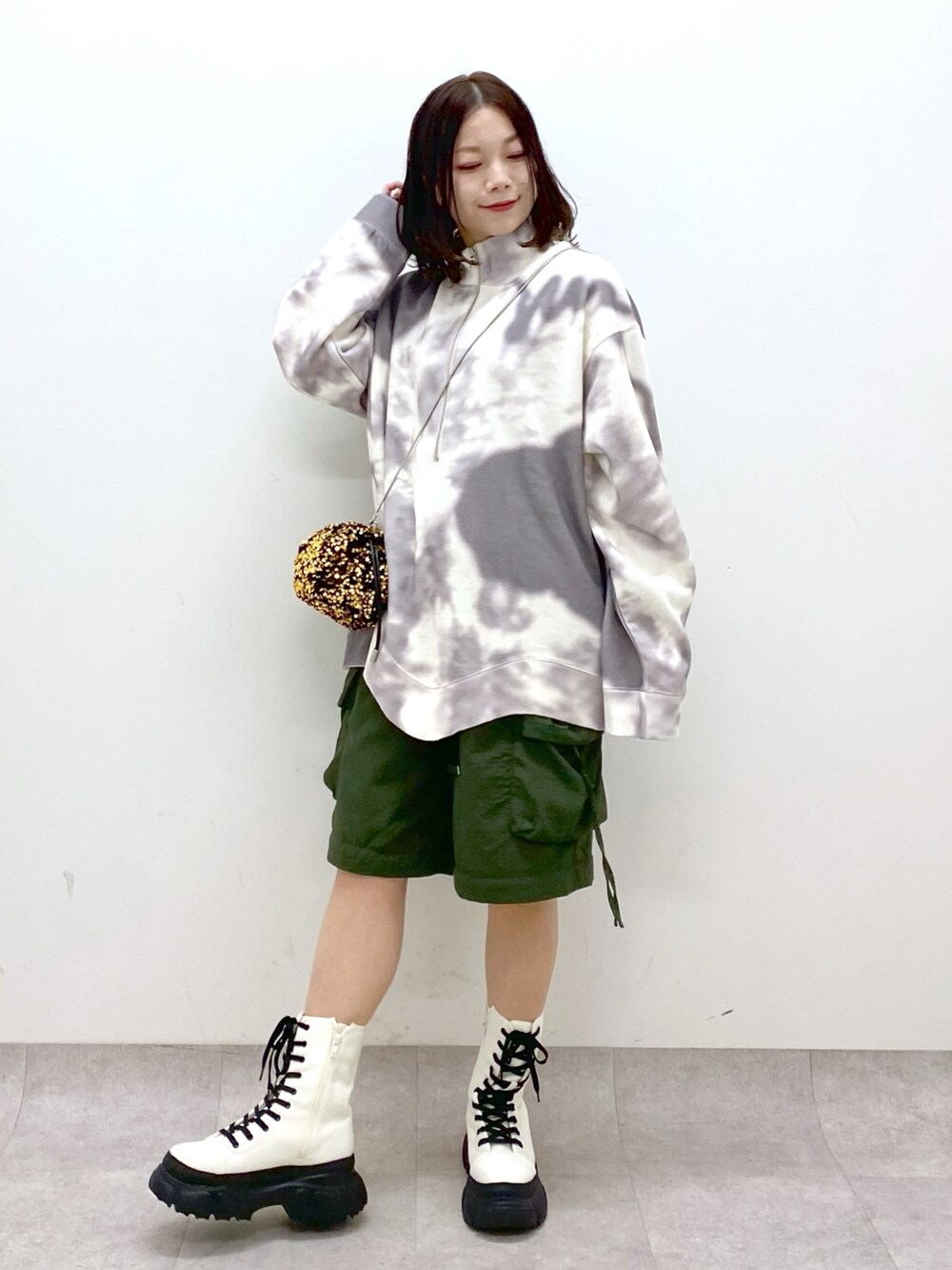 グリーン系のカーゴパンツ、ホワイト系のブーツ、ゴールド系のショルダーバッグを着用したレディースの冬コーディネートの4枚目の写真