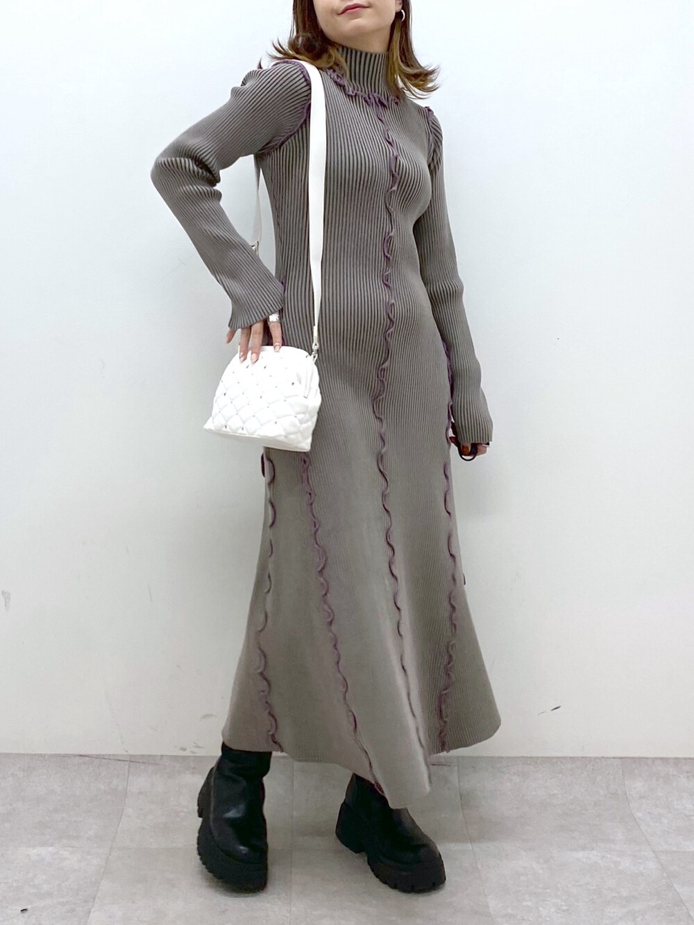 ブラウン系のワンピース、ホワイト系のショルダーバッグ、ブラック系のブーツを着用したレディースの秋コーディネートの7枚目の写真