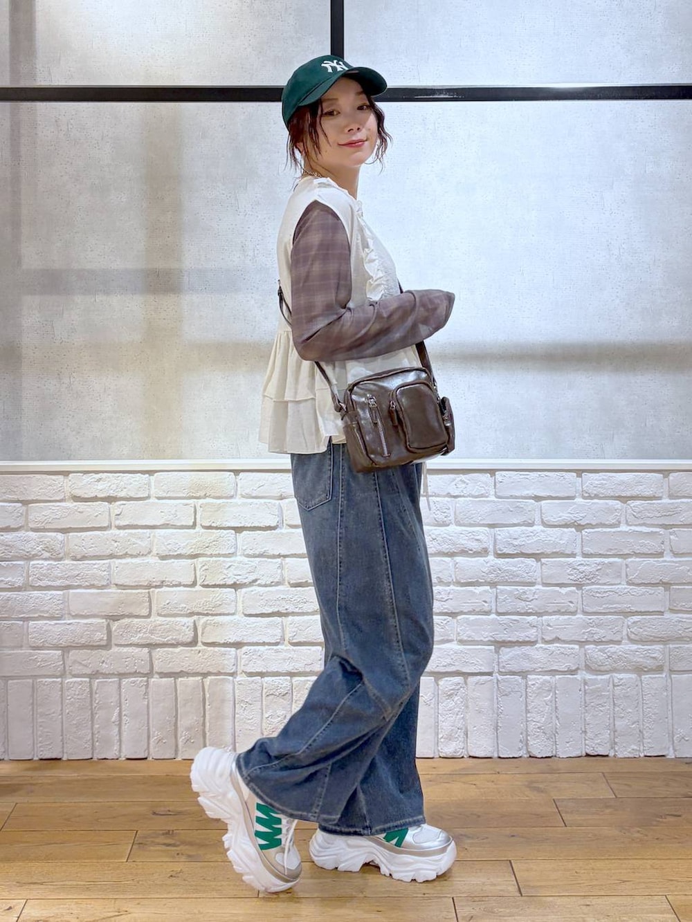 ホワイト系のスニーカー、ブラウン系のショルダーバッグ、ブルー系のデニムパンツを着用したレディースの春コーディネートの5枚目の写真