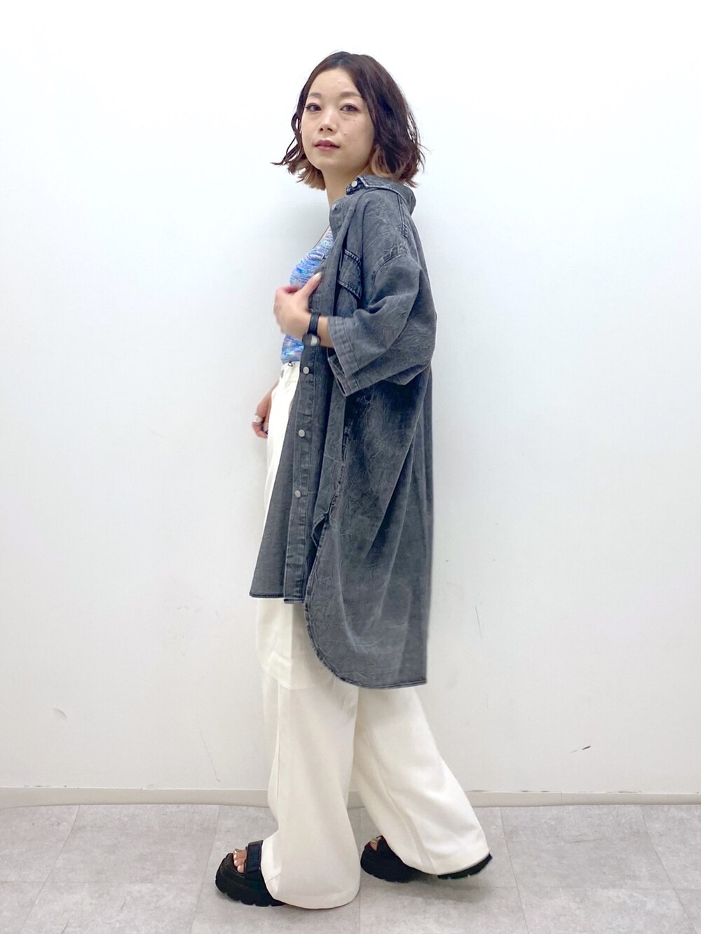 ホワイト系のカーゴパンツ、ブルー系のタンクトップ、ブラック系のサンダルを着用したレディースの夏コーディネートの2枚目の写真