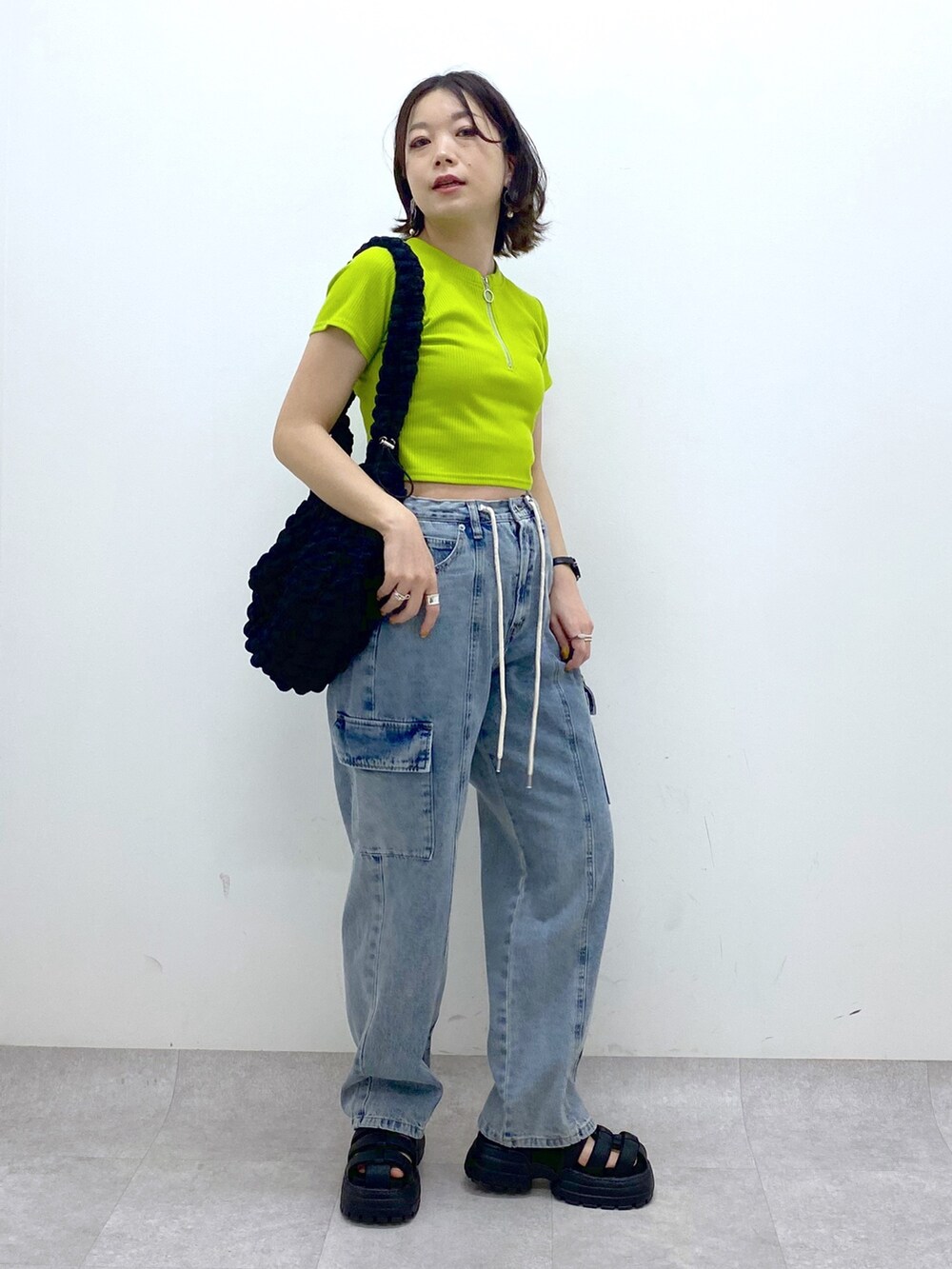 ブルー系のデニムパンツ、ブラック系のバッグ、イエロー系のTシャツ/カットソーを着用したレディースの春コーディネートの2枚目の写真