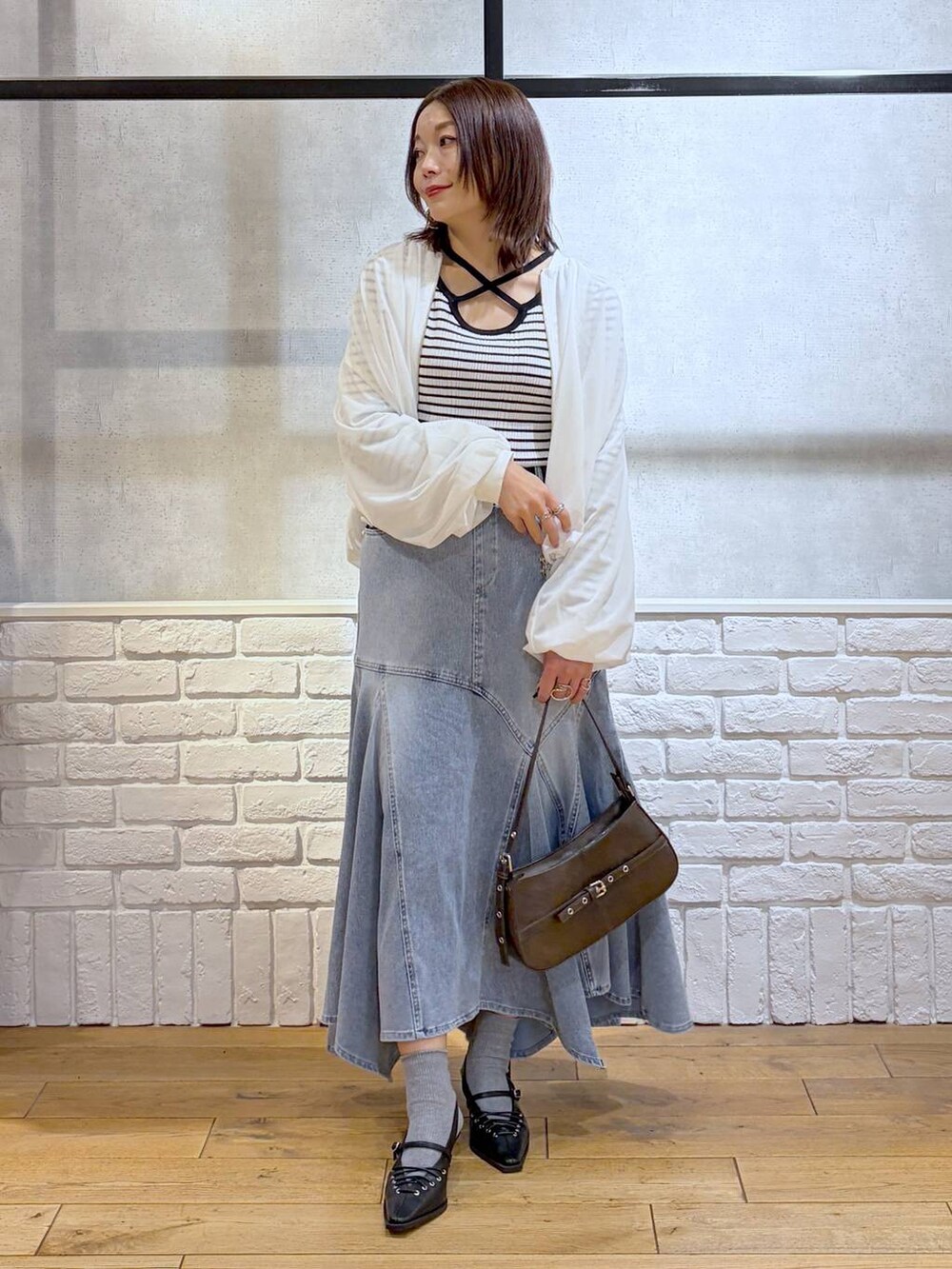 ブラウン系のハンドバッグ、ホワイト系のニット/セーター、ブラック系のサンダルを着用したレディースの春コーディネートの4枚目の写真