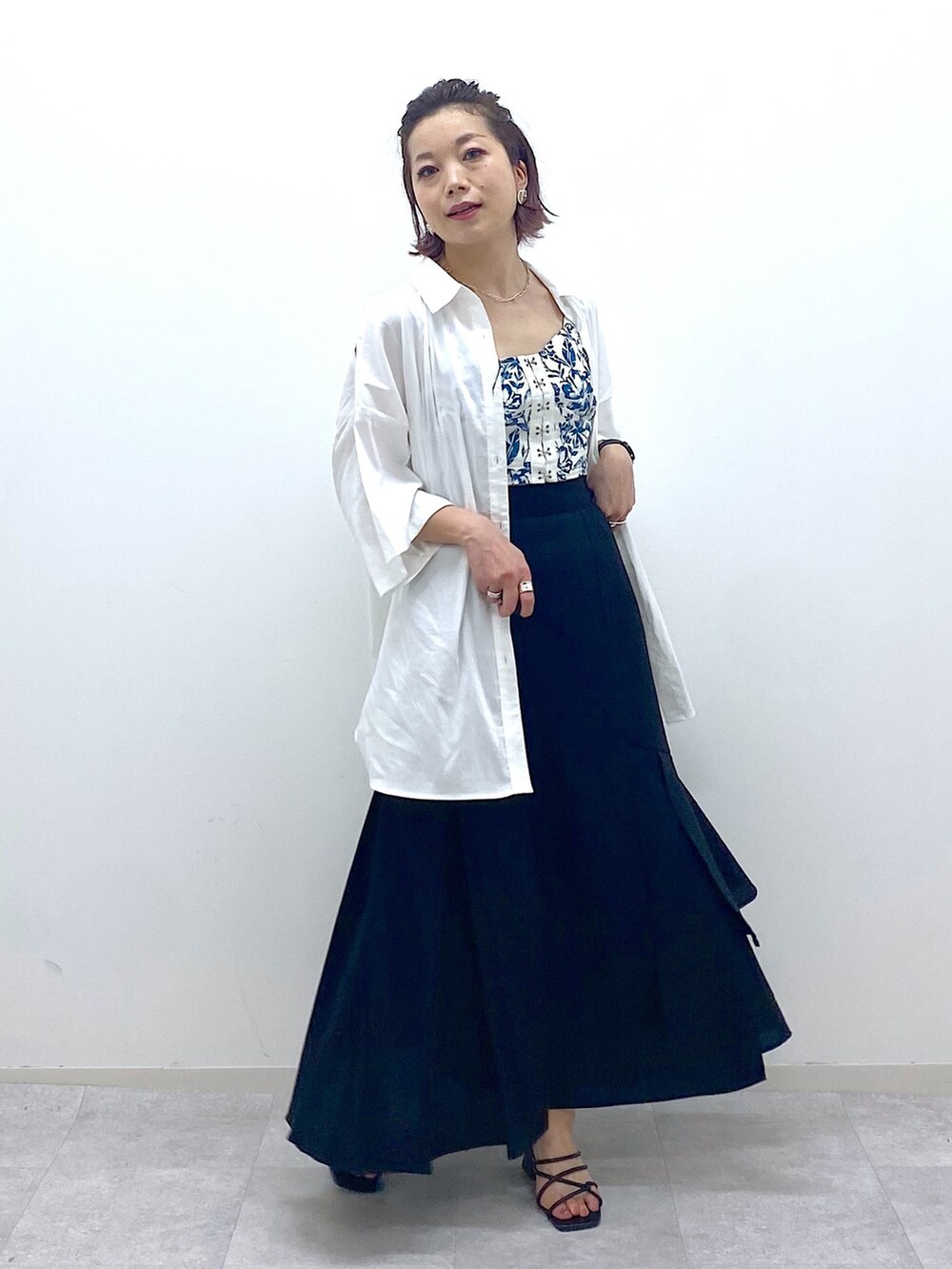 ブラック系のスカート、ブラック系のサンダル、ホワイト系のシャツ/ブラウスを着用したレディースの夏コーディネートの4枚目の写真