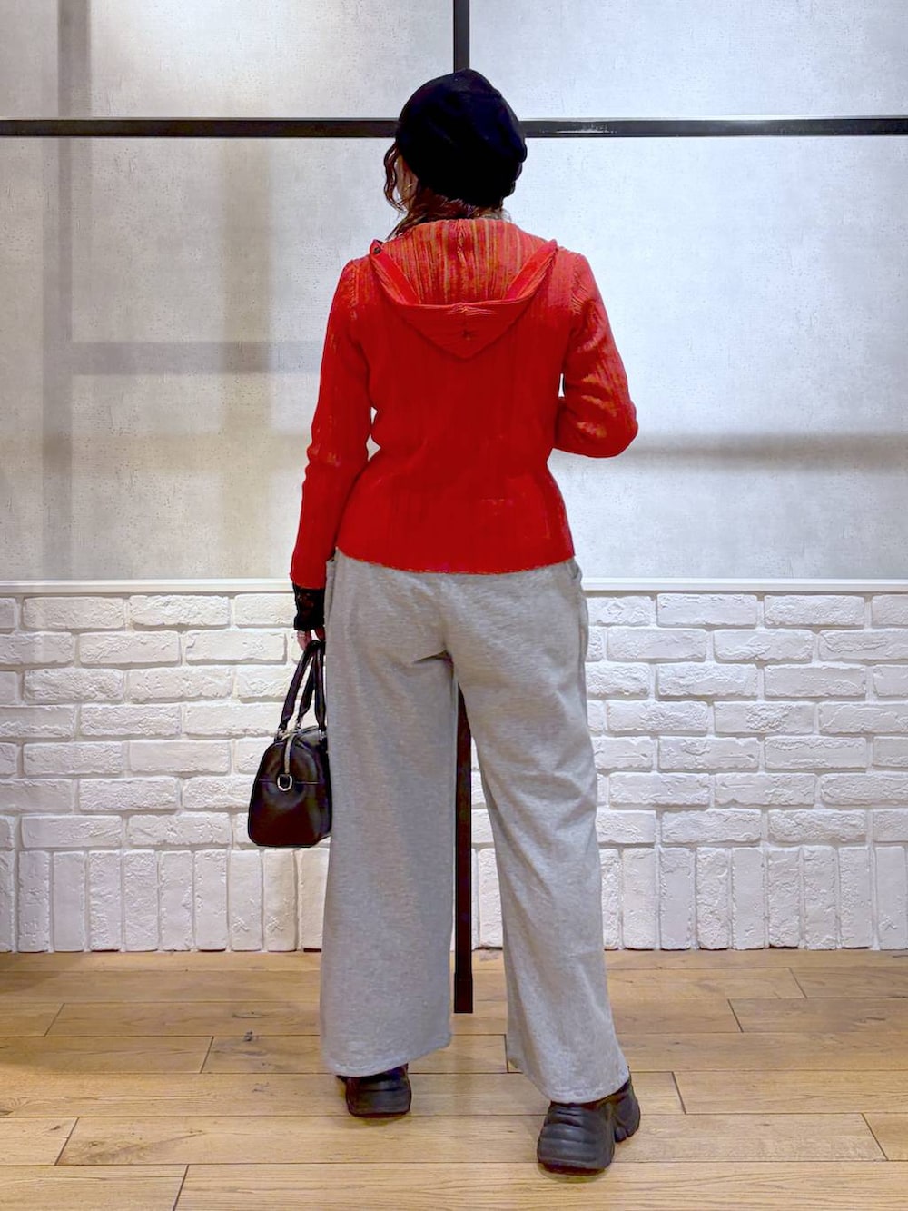 ブラック系のスニーカー、ブラック系のボストンバッグ、レッド系のカーディガン/ボレロを着用したレディースの春コーディネートの6枚目の写真