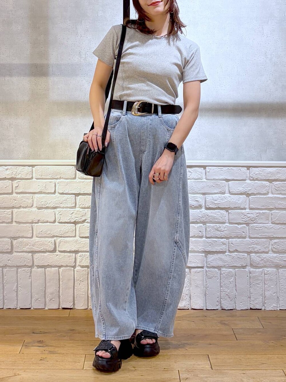 ブルー系のデニムパンツ、ブラック系のショルダーバッグ、ブラック系のサンダルを着用したレディースの春コーディネートの3枚目の写真
