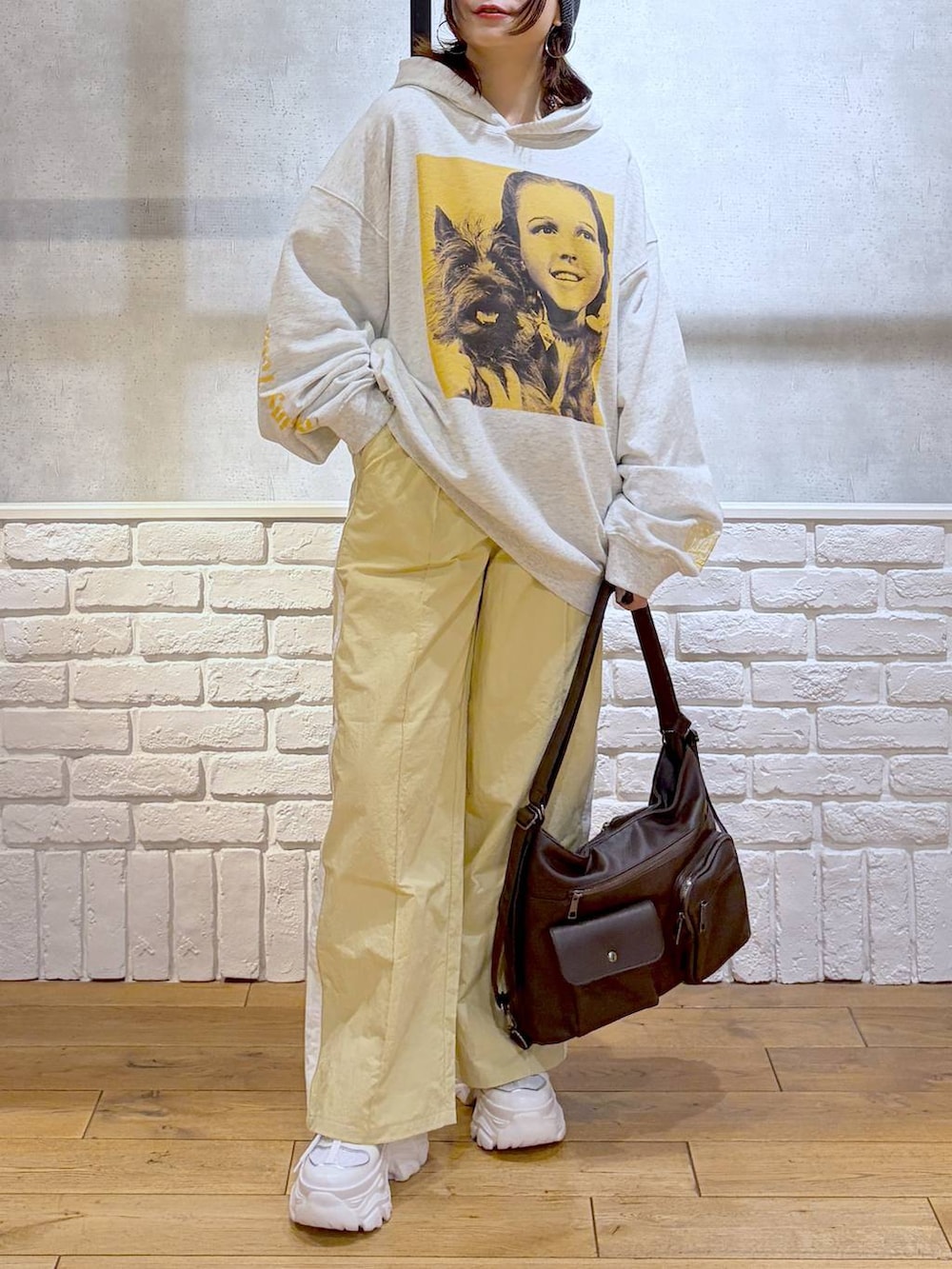 ホワイト系のスニーカー、イエロー系のスウェットパンツ、ブラウン系のショルダーバッグを着用したレディースの春コーディネートの3枚目の写真