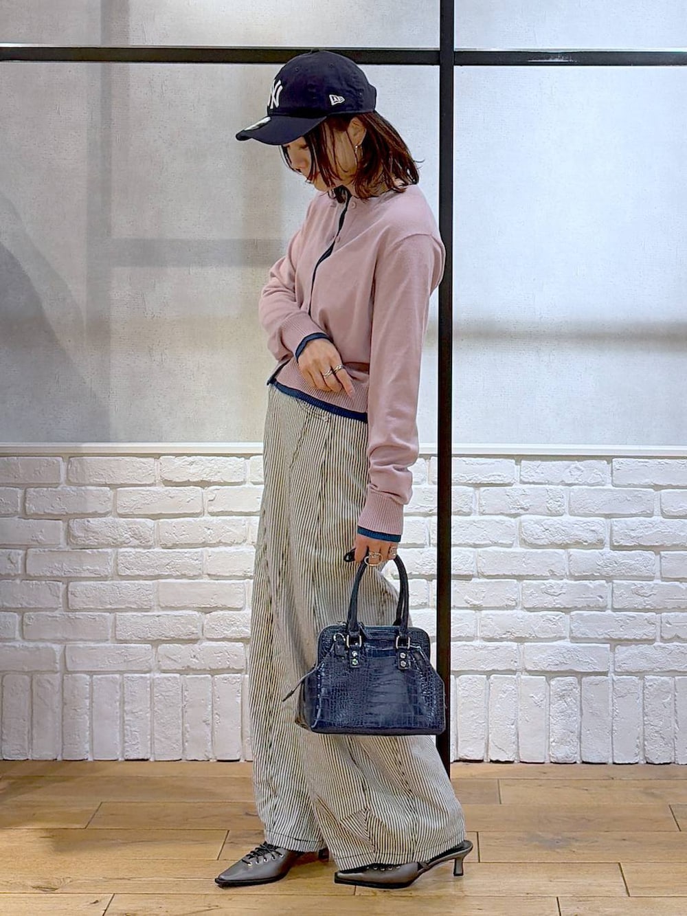 ブルー系のハンドバッグ、ブラウン系のサンダル、ブラック系のデニムパンツを着用したレディースの冬コーディネートの8枚目の写真