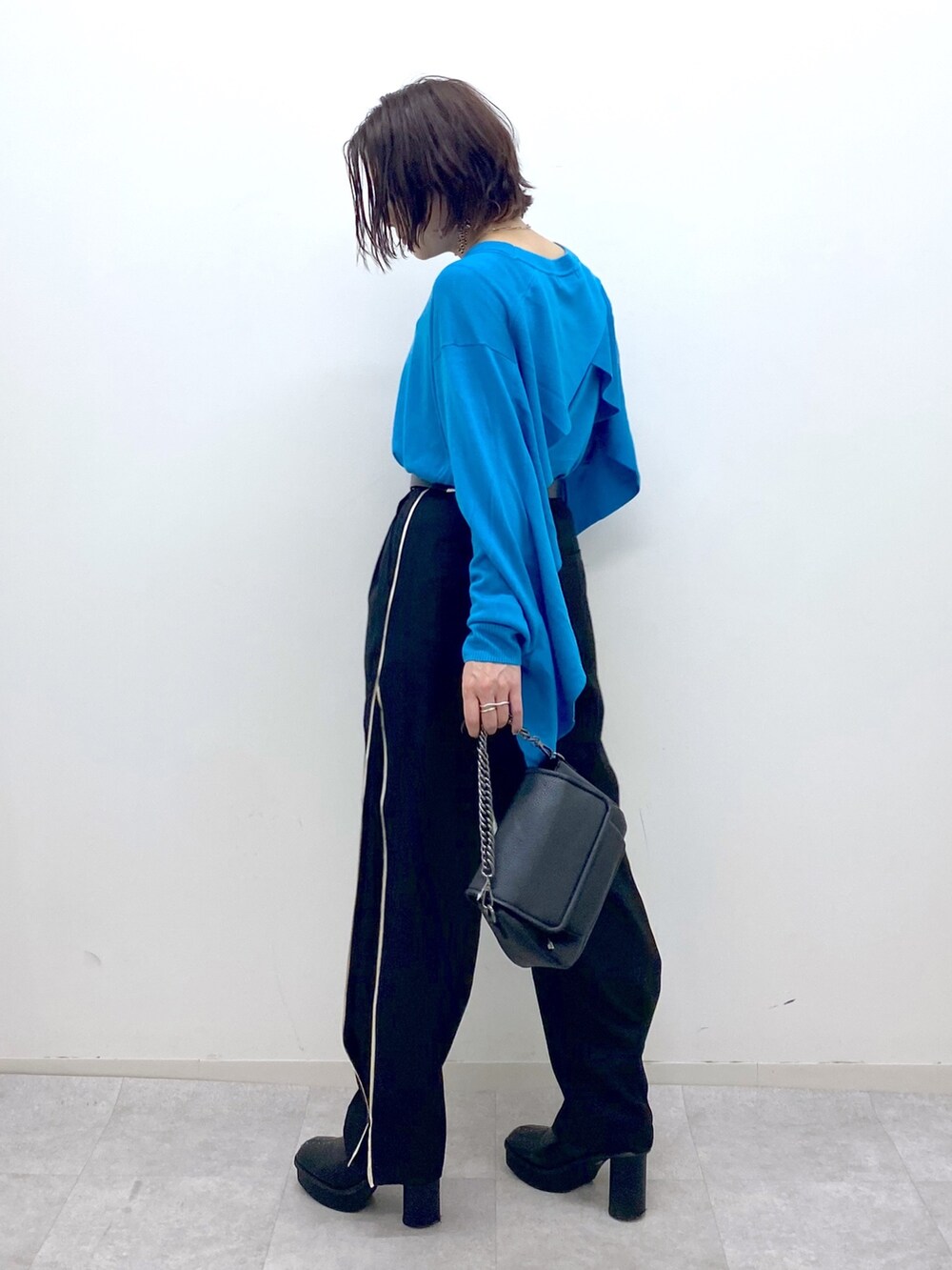 ブラック系のブーツ、ブラック系のパンツ、ブラック系のバッグを着用したレディースの秋コーディネートの2枚目の写真