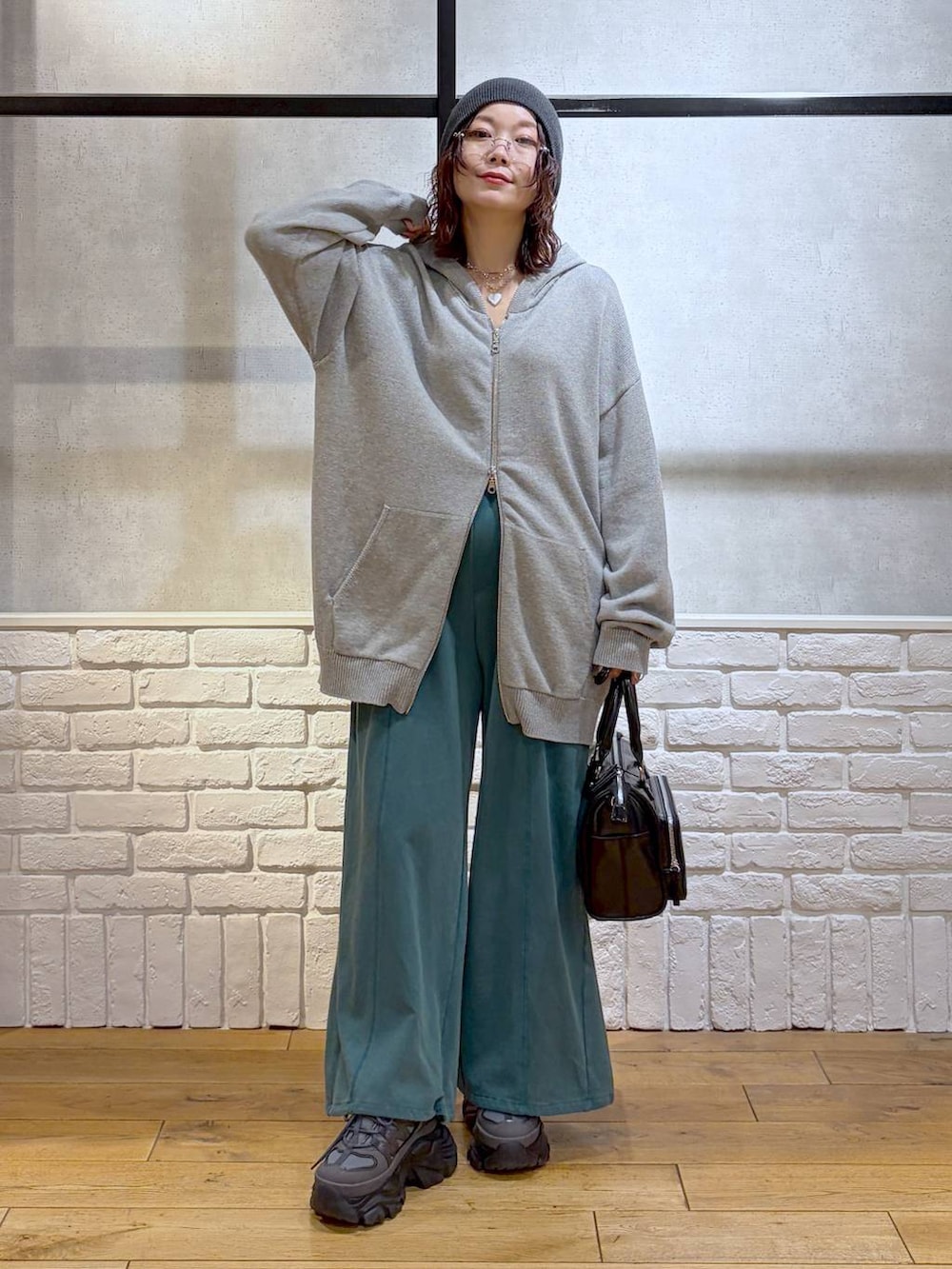 グレー系のスニーカー、グレー系のパーカー、ブラック系のショルダーバッグを着用したレディースの春コーディネートの4枚目の写真