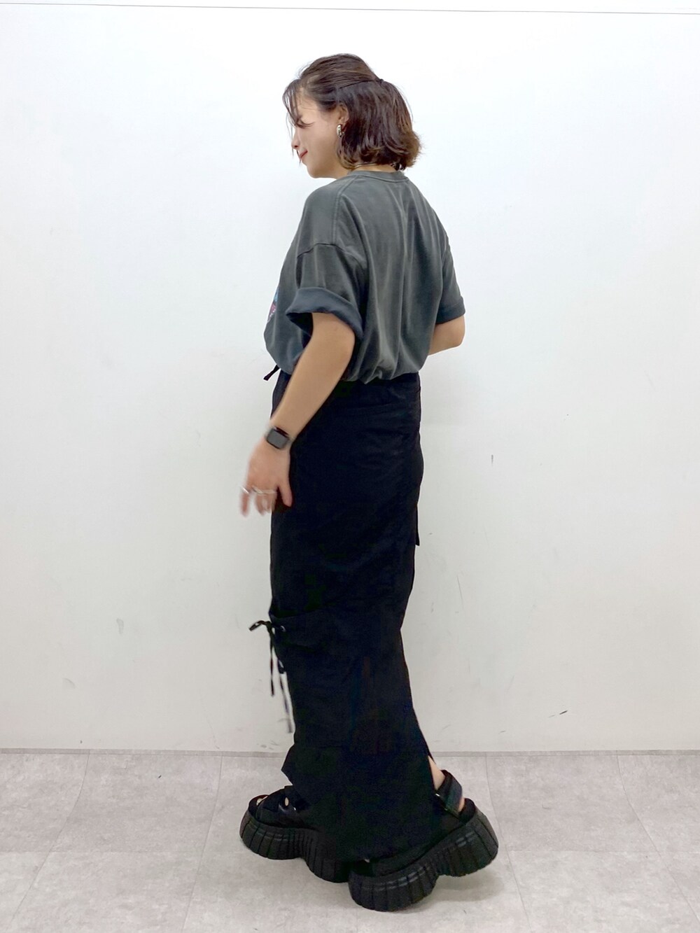 グレー系のTシャツ/カットソー、ブラック系のスカート、ブラック系のスニーカーを着用したレディースの夏コーディネートの7枚目の写真