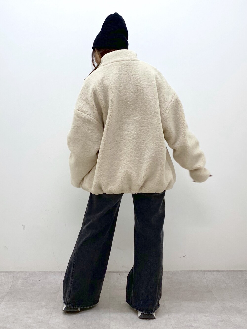 ホワイト系のブルゾン、ブラック系のニット/セーター、ブラック系のデニムパンツを着用したレディースの秋コーディネートの4枚目の写真