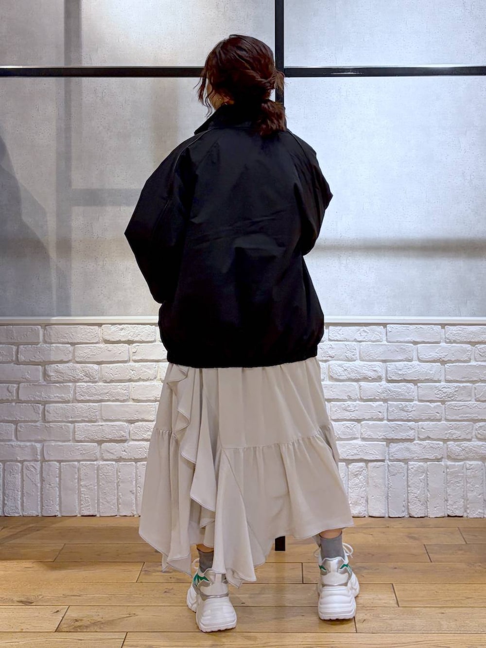 ホワイト系のスニーカー、ベージュ系のスカート、ブラック系のナイロンジャケットを着用したレディースの冬コーディネートの6枚目の写真
