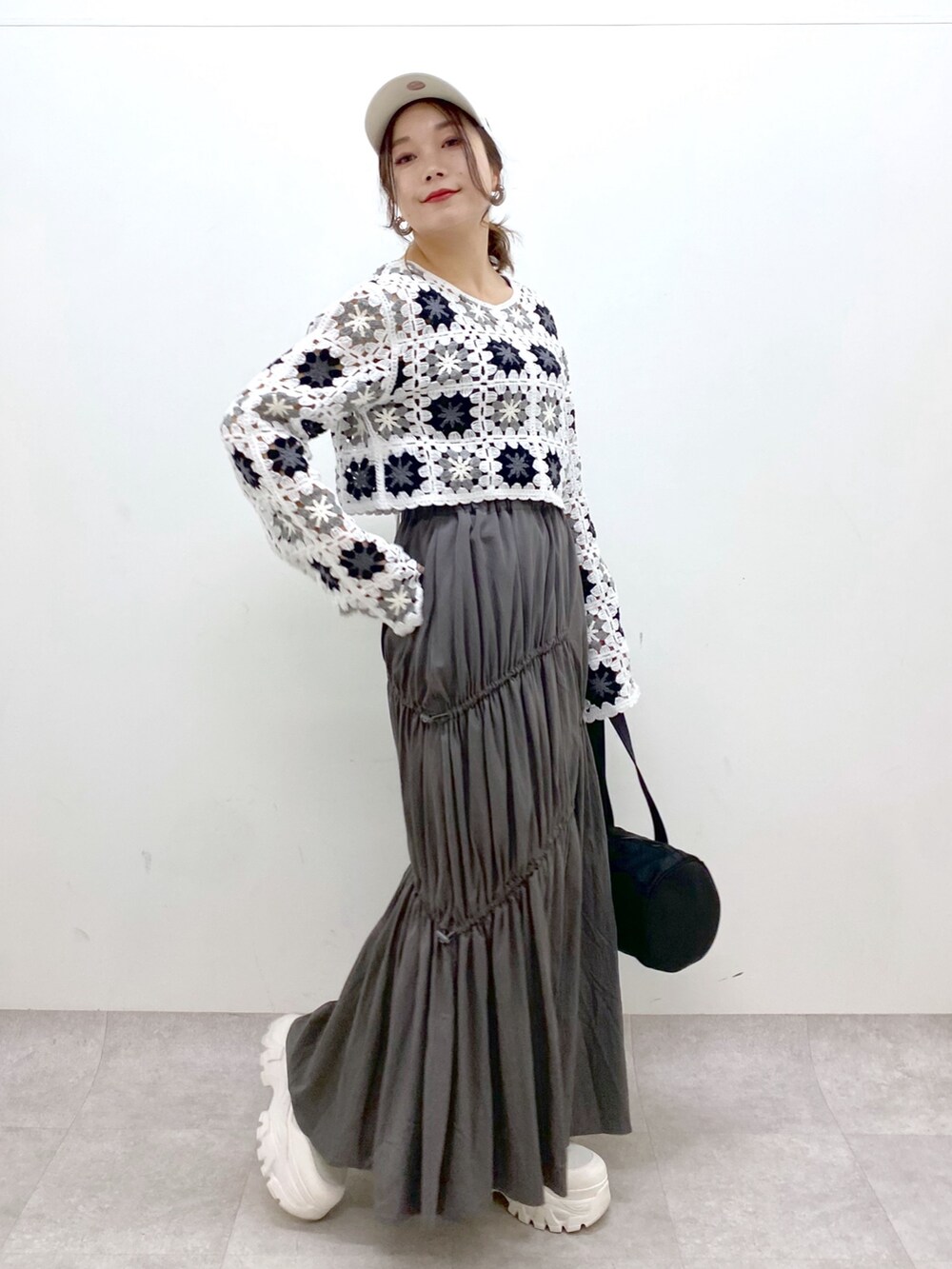 グレー系のスカート、ホワイト系のカーディガン/ボレロ、ブラック系のドラムバッグを着用したレディースの春コーディネートの7枚目の写真